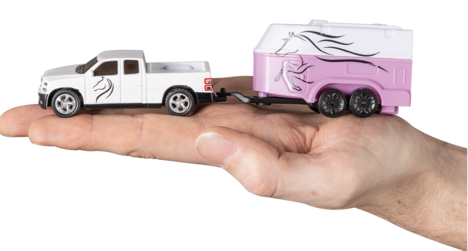 Hand, die ein weißes Spielzeugauto und einen rosa Pferdeanhänger hält.