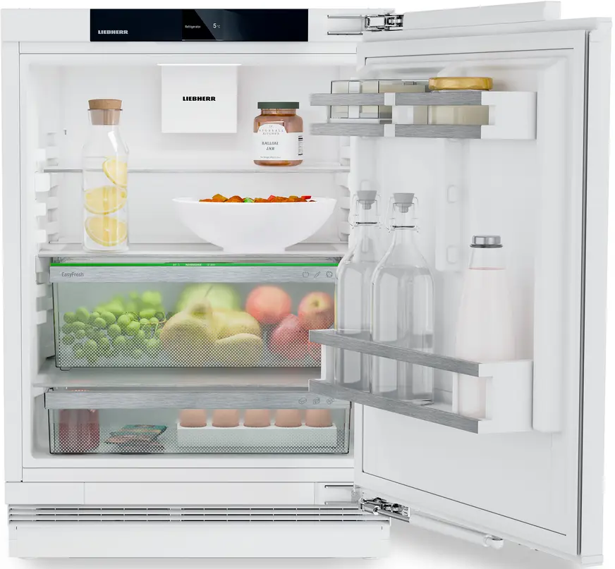 Ein weißer Kühlschrank mit Lebensmitteln: Früchte, Gläser, Flaschen und eine Schüssel.