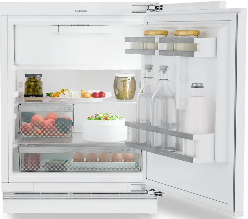 Weißer Kühlschrank mit offener Tür. Im Inneren befinden sich Lebensmittel: Obst, Gemüse und Flaschen.