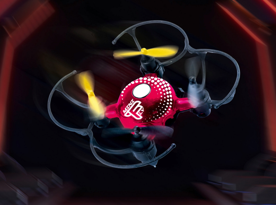 Eine rote und schwarze Mini TL Drohne im Flug, mit gelben Propellern und dunklem Hintergrund.