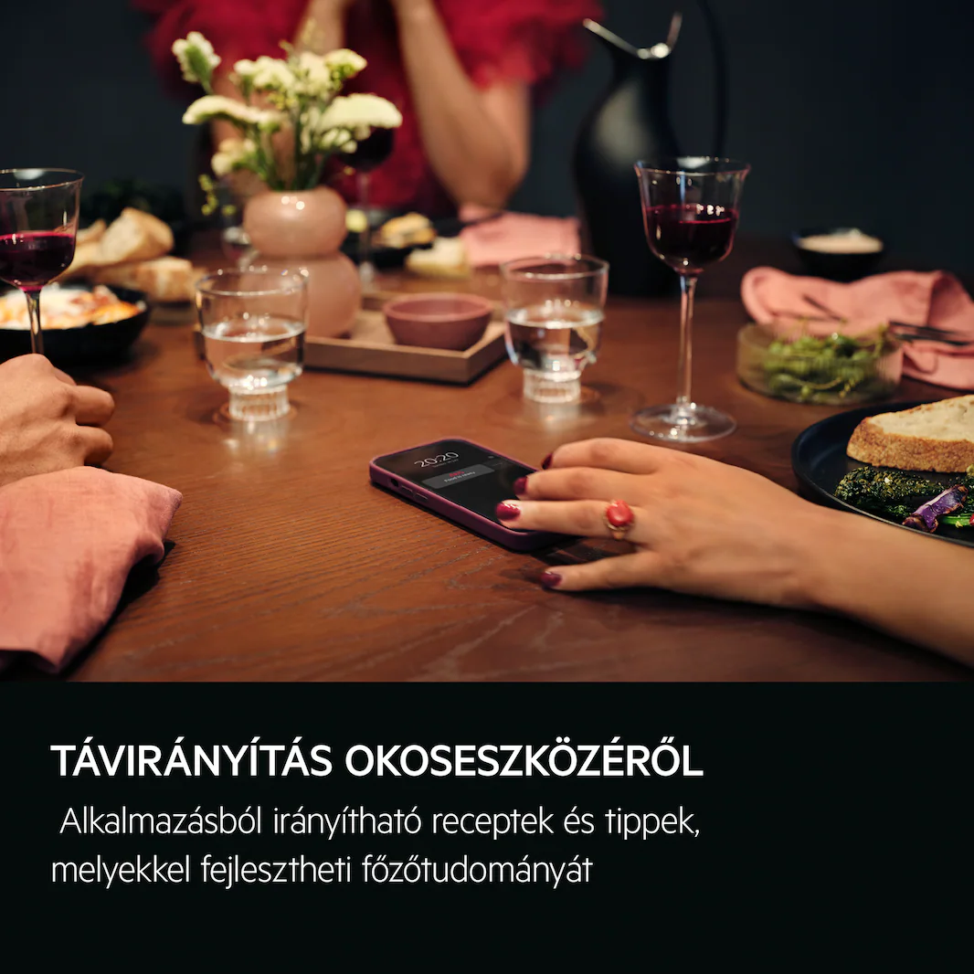 Emberek vacsoráznak borospoharakkal és egy 2020-at mutató telefonnal. Étel és virágváza is van.