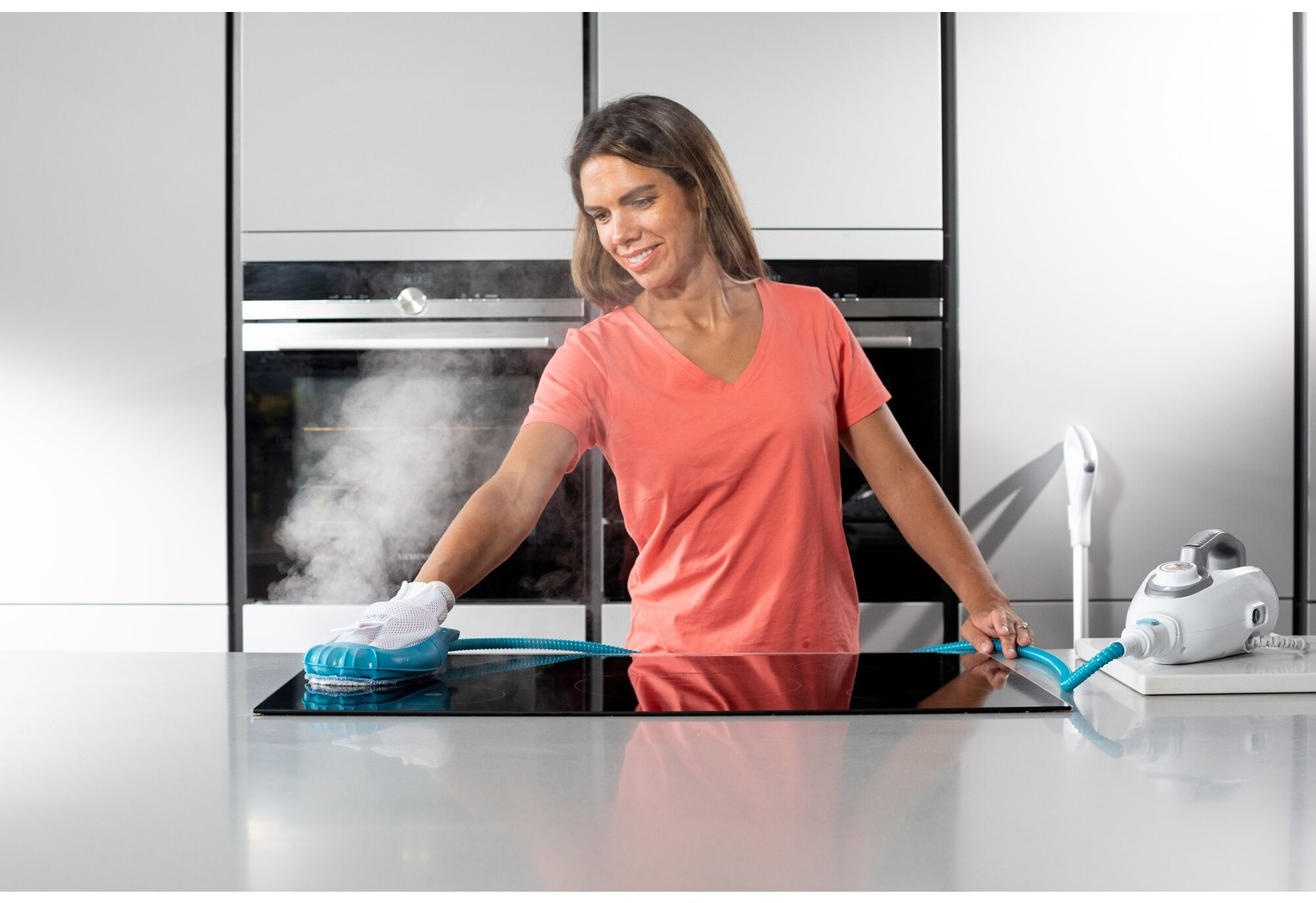 Femme utilisant un nettoyeur vapeur sur une plaque de cuisson noire.