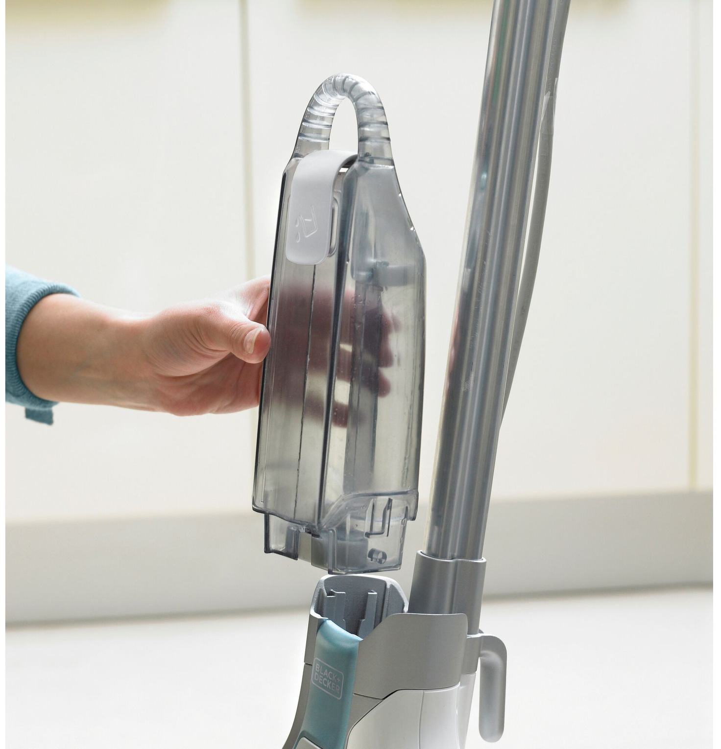 La mano di una persona sta rimuovendo il serbatoio dell'acqua da una scopa a vapore. Il marchio Black+Decker è visibile.