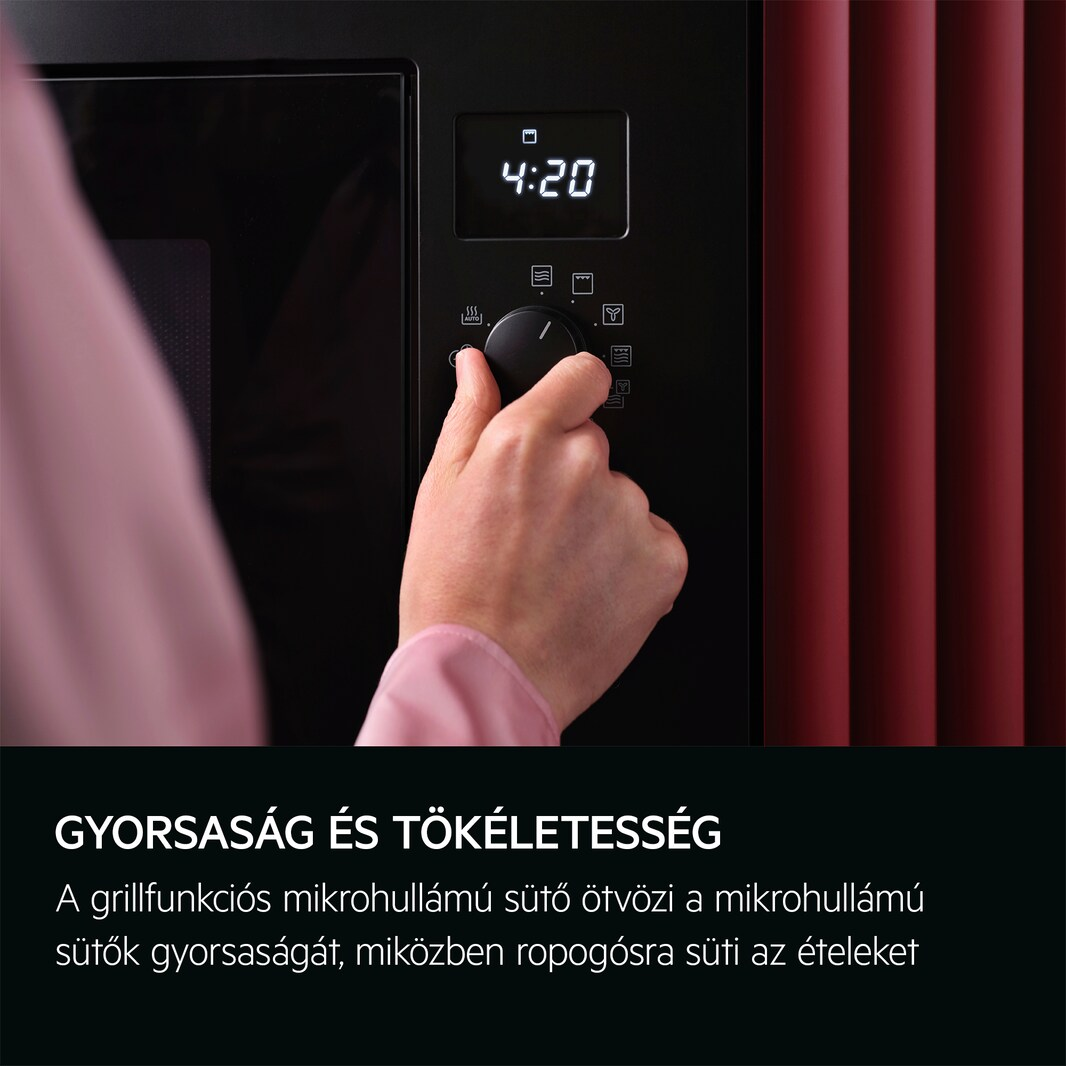 Egy nő keze a fekete mikrohullámú sütő tárcsáját állítja, a digitális kijelzőn az idő látható.
