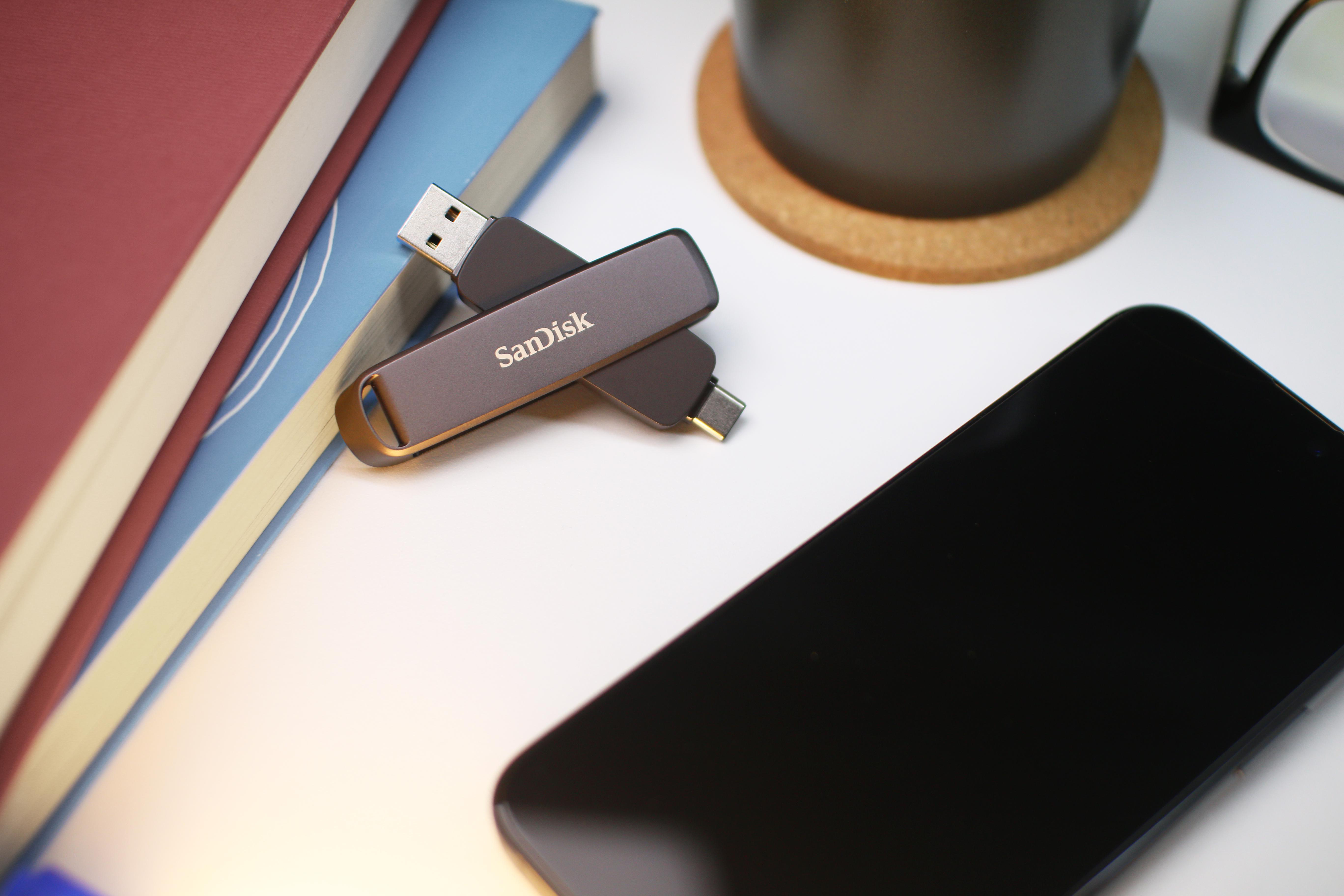 Ein Telefon und zwei USB-Sticks auf einer weißen Oberfläche neben Büchern.