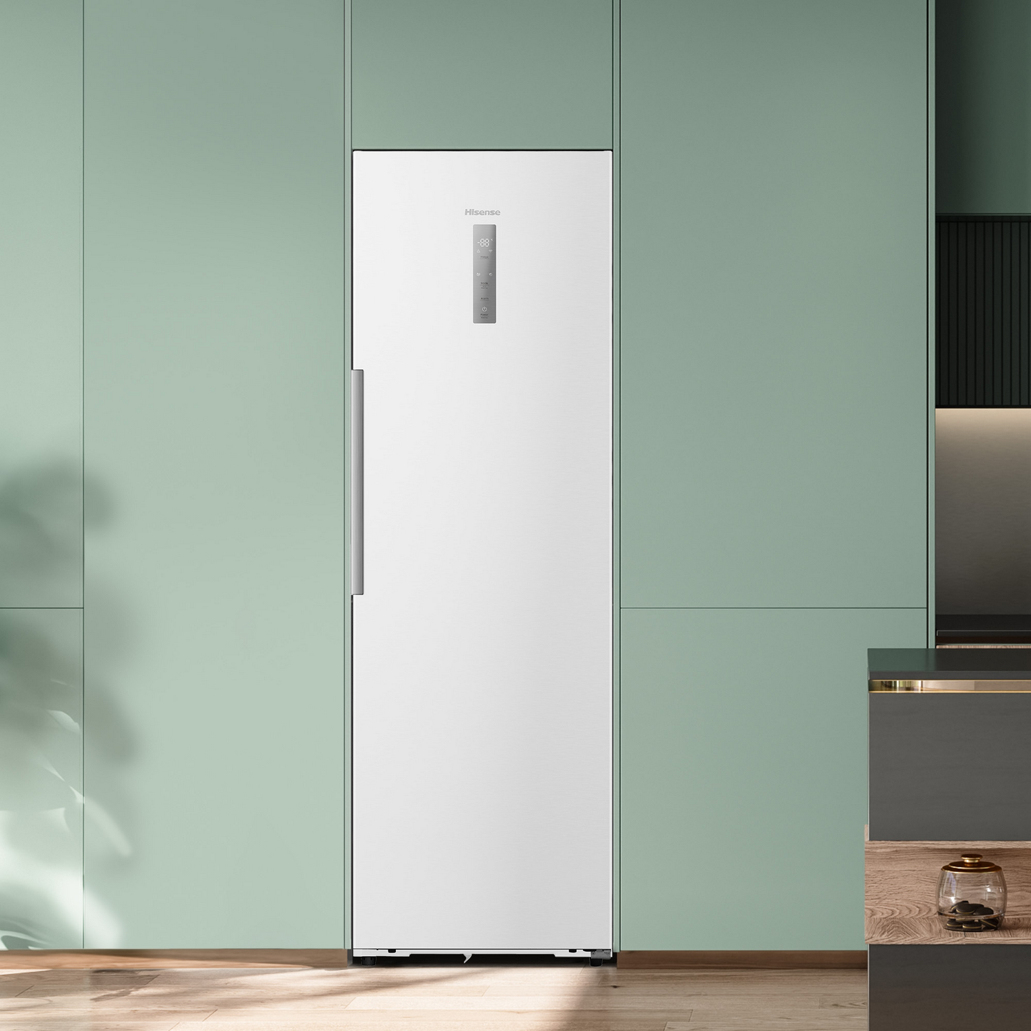 Un refrigerador blanco está contra una pared verde claro.