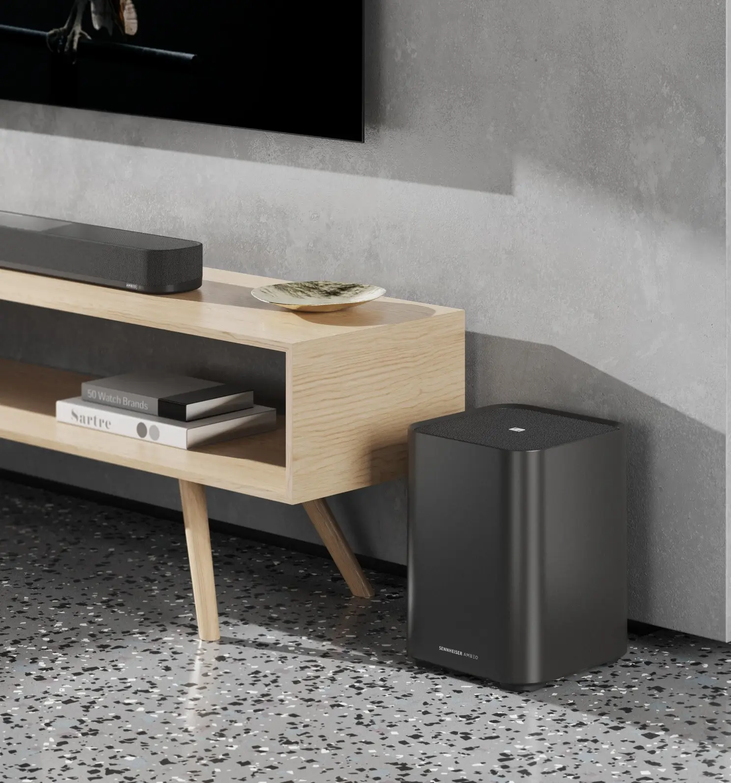 Une barre de son noire sur un support en bois avec des livres et un caisson de basses sur un sol à motifs.