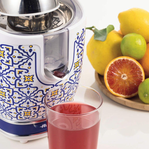 Extractor de zumo con fruta y zumo. Se ven naranjas, limones y un vaso de zumo.