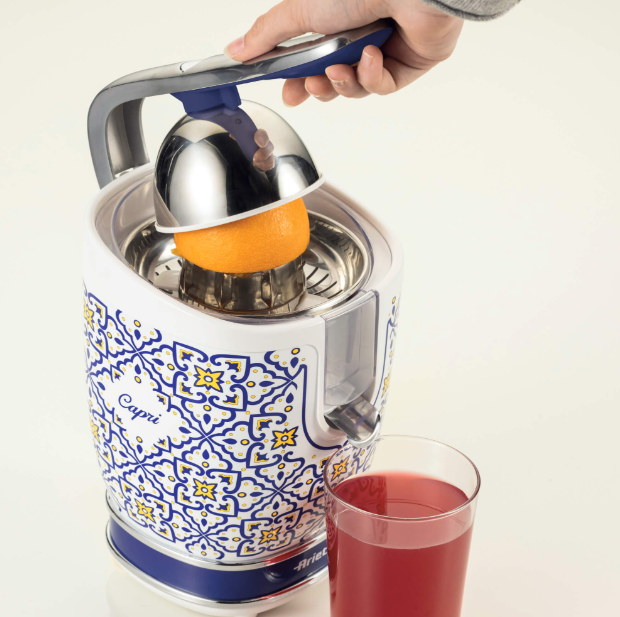 Exprimidor con una naranja exprimiéndose, un vaso de zumo delante, diseño blanco y azul.