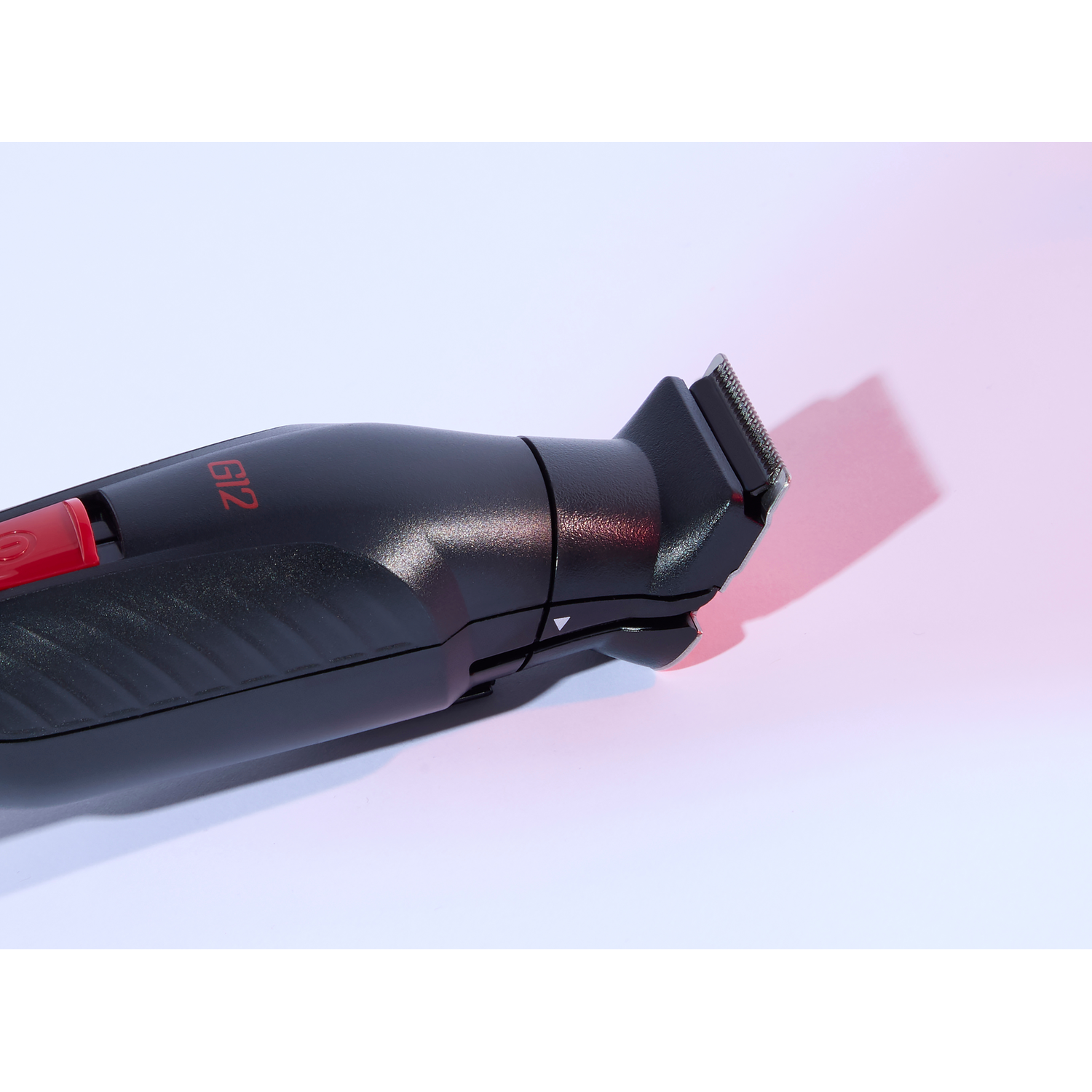 Close-up of a black hair trimmer with red accents, angled on a white surface.