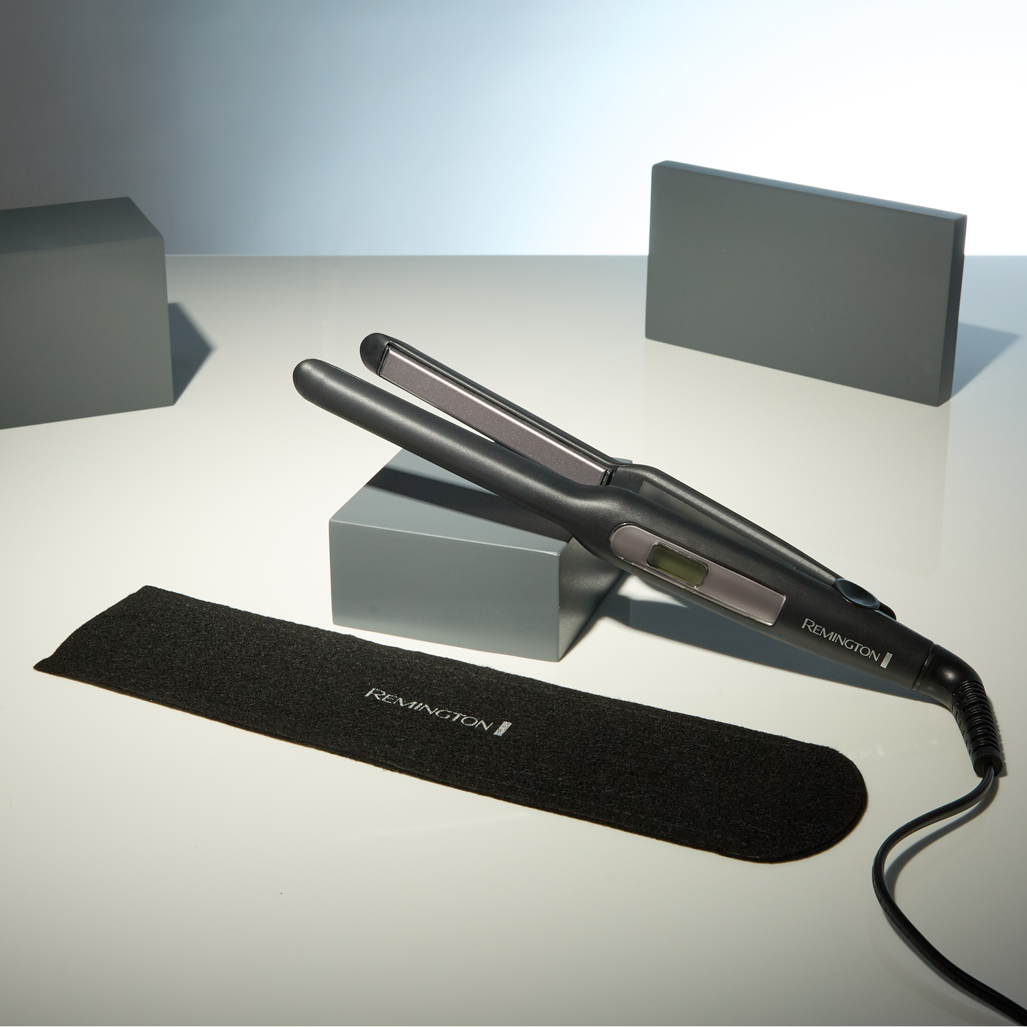 A black and gray flat iron with a Remington logo and case.