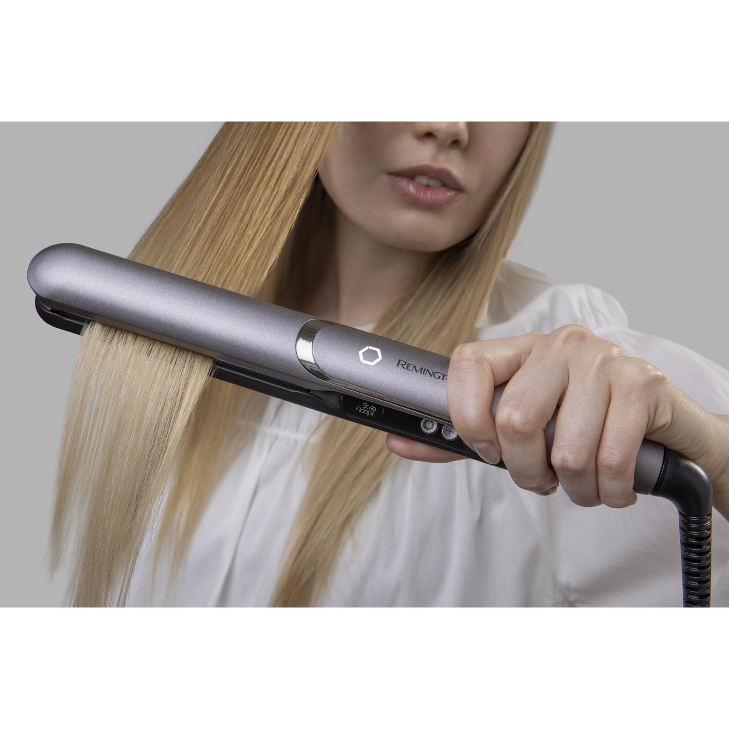 Woman straightening her hair with a flat iron.