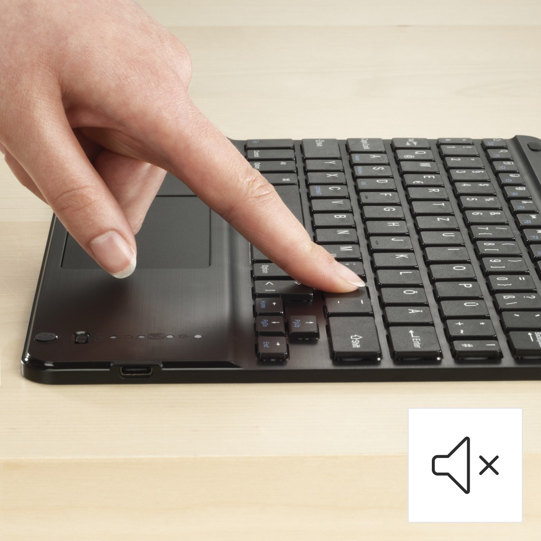 Eine Hand drückt eine Taste auf einer schwarzen Tastatur. Ein Ton aus-Symbol befindet sich unten rechts.