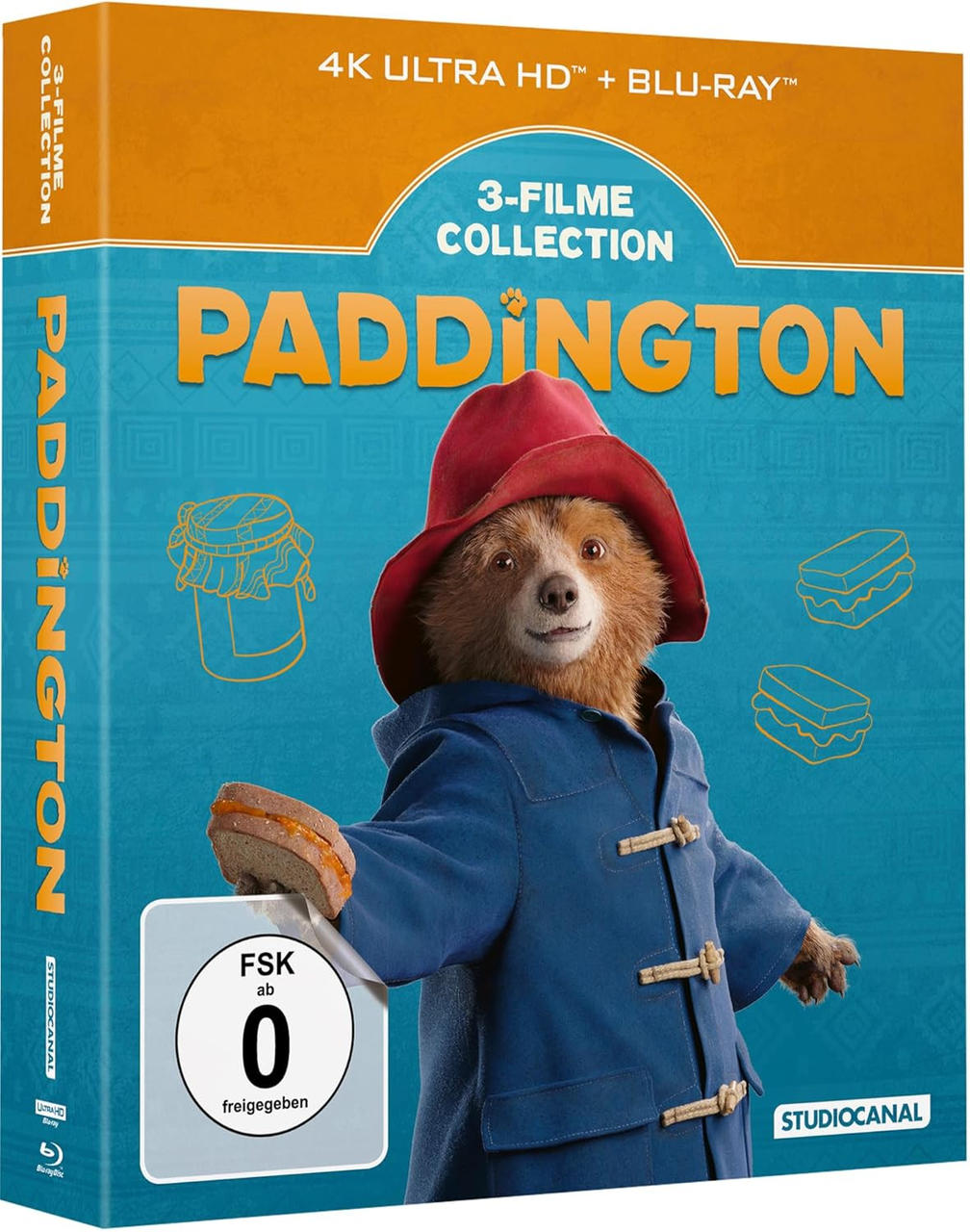 Paddington-Bär in blauem Mantel hält Sandwich, Box-Art.