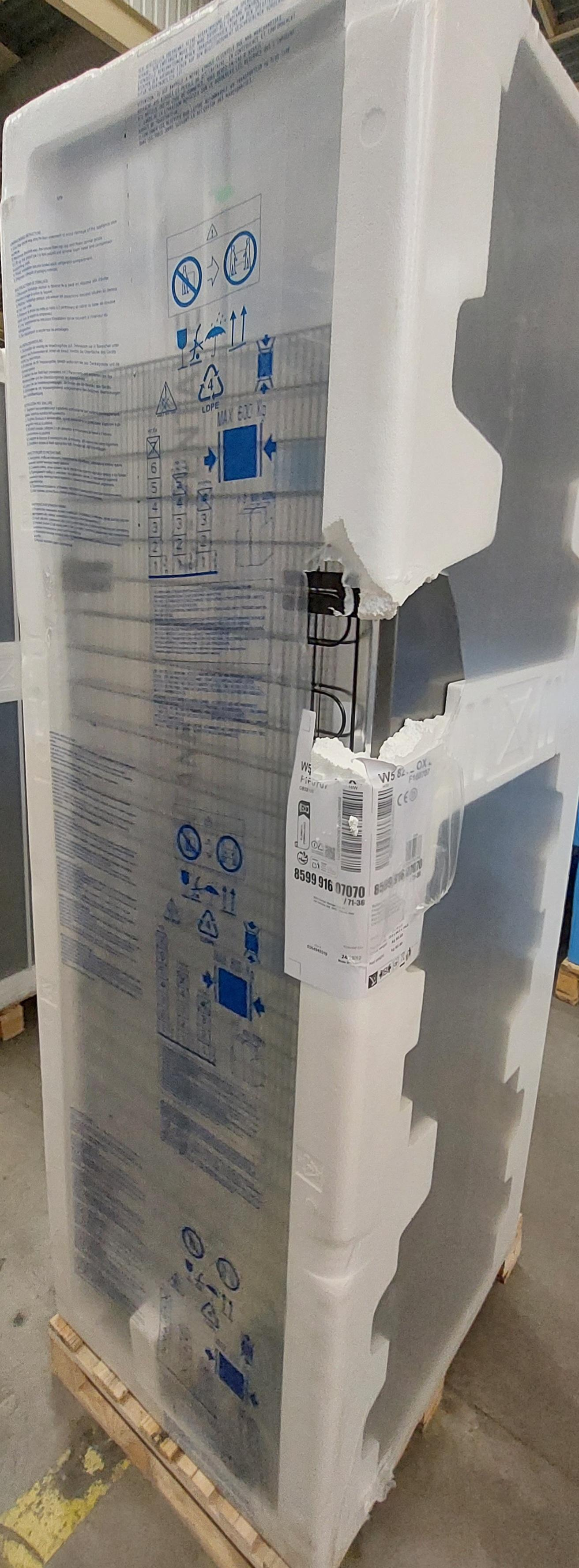 Lodówka, owinięta w plastik, stoi na palecie.