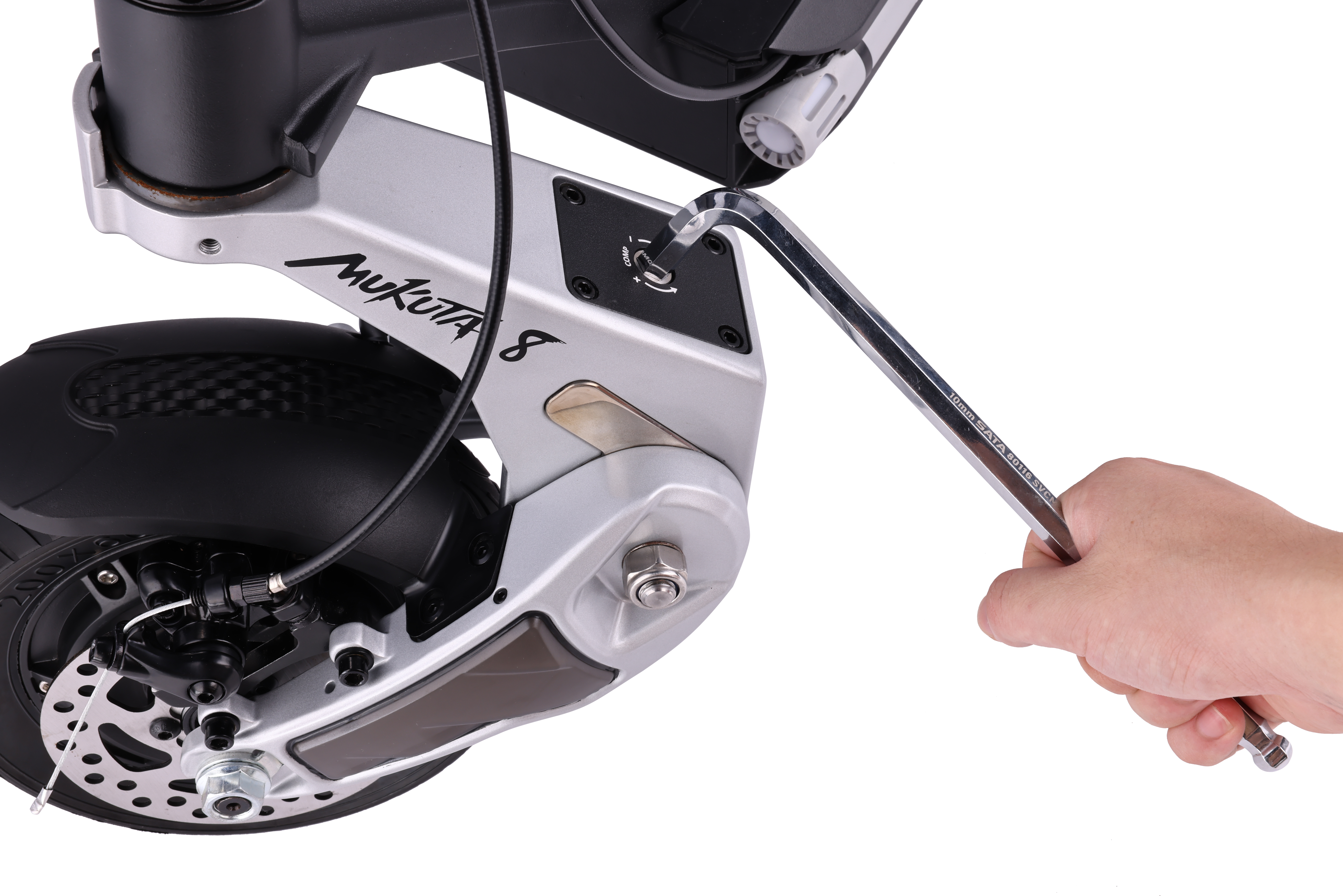 Bir kişi, bir scooter'da bir cıvatayı sıkmak için bir anahtar kullanıyor. Scooter gümüş renginde.