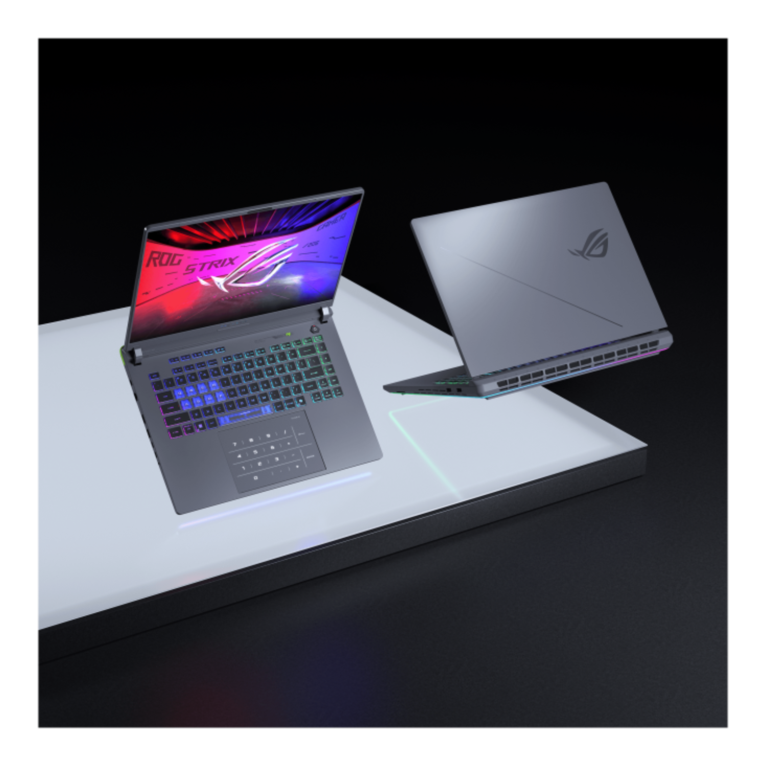 Two black ROG Strix laptops, one open, on a platform with a black background.