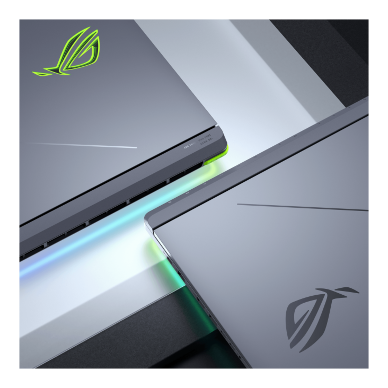 Two gray laptops angled towards each other with the ROG logo. Shiny surface. Dark background.