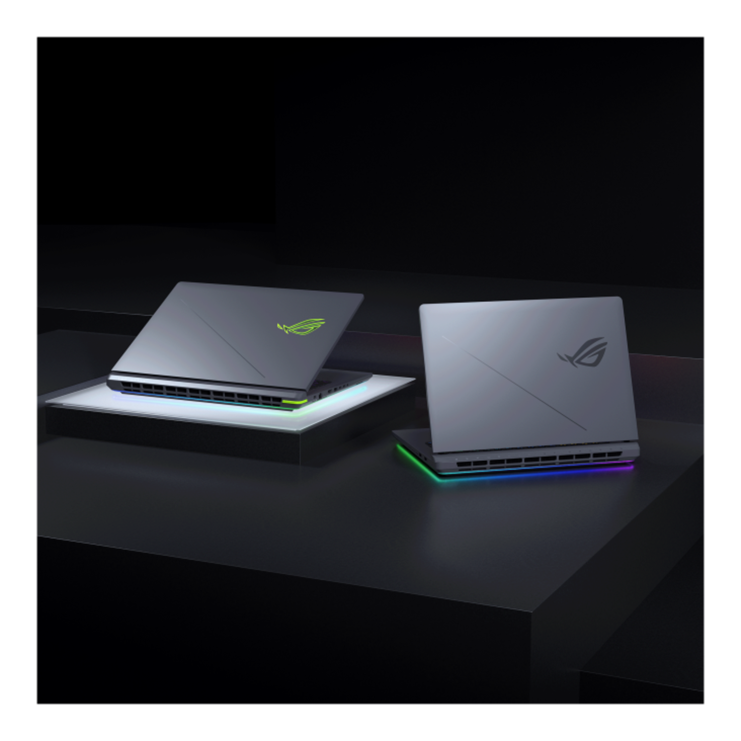 Two grey laptops with ROG logo on stand, angled towards camera.