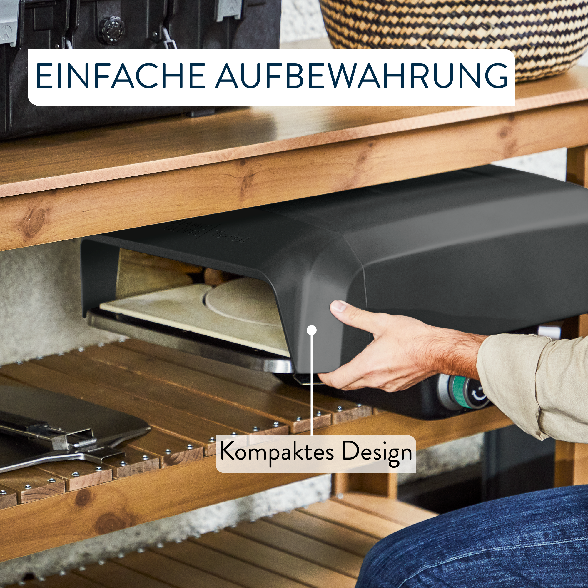 Eine Person hält einen schwarzen Pizzaofen auf einem Holzregal. Die Szene umfasst einen Korb und Text.