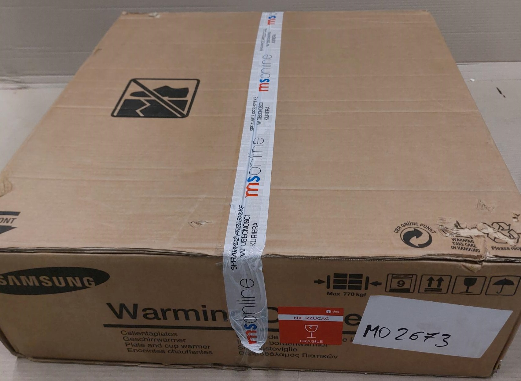 Kartonowe pudełko z taśmą i tekstem, w tym naklejką ostrzegawczą.