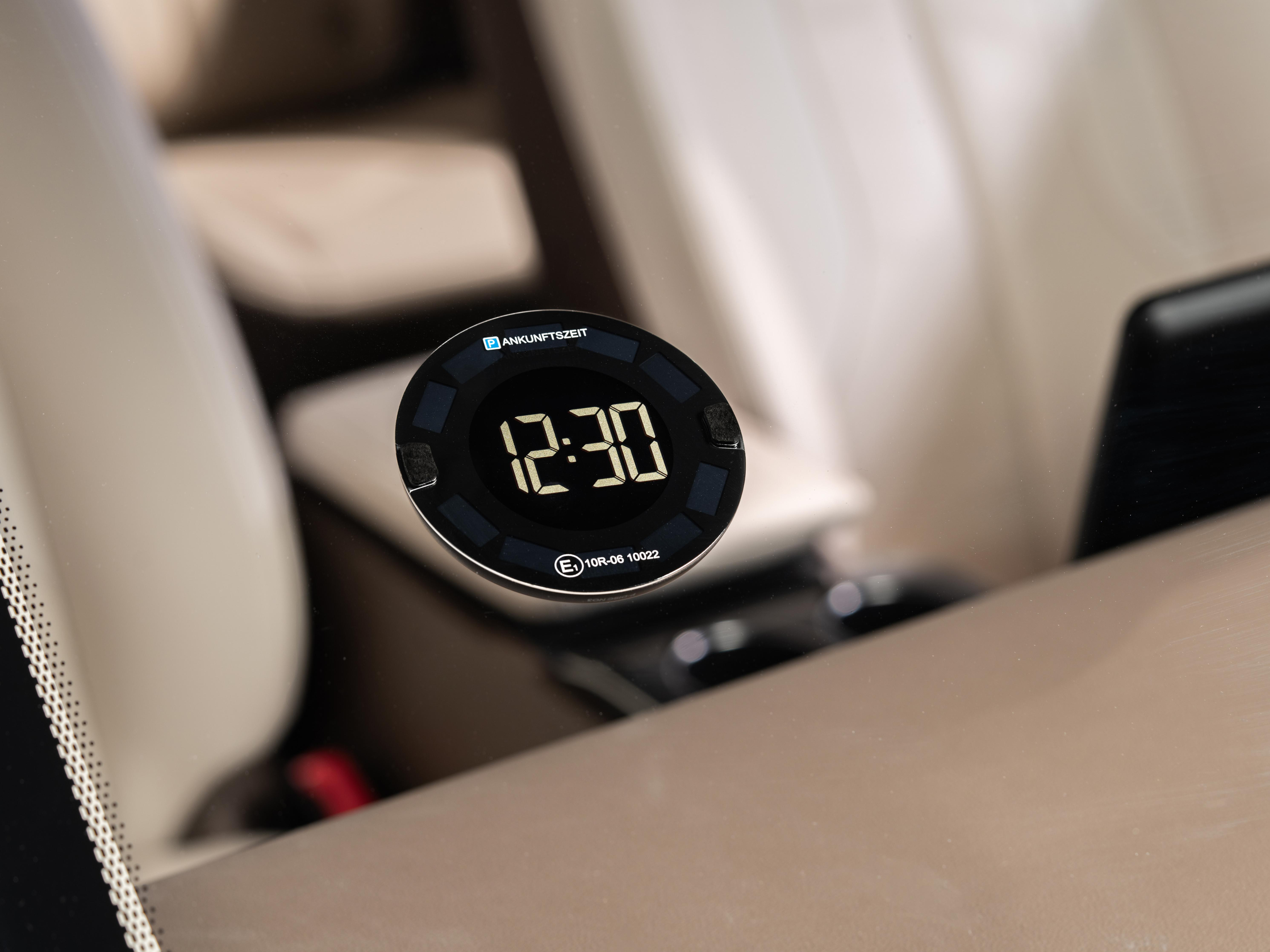 Autouhr zeigt 12:30 mit schwarzem Hintergrund und weißem Autointerieur.