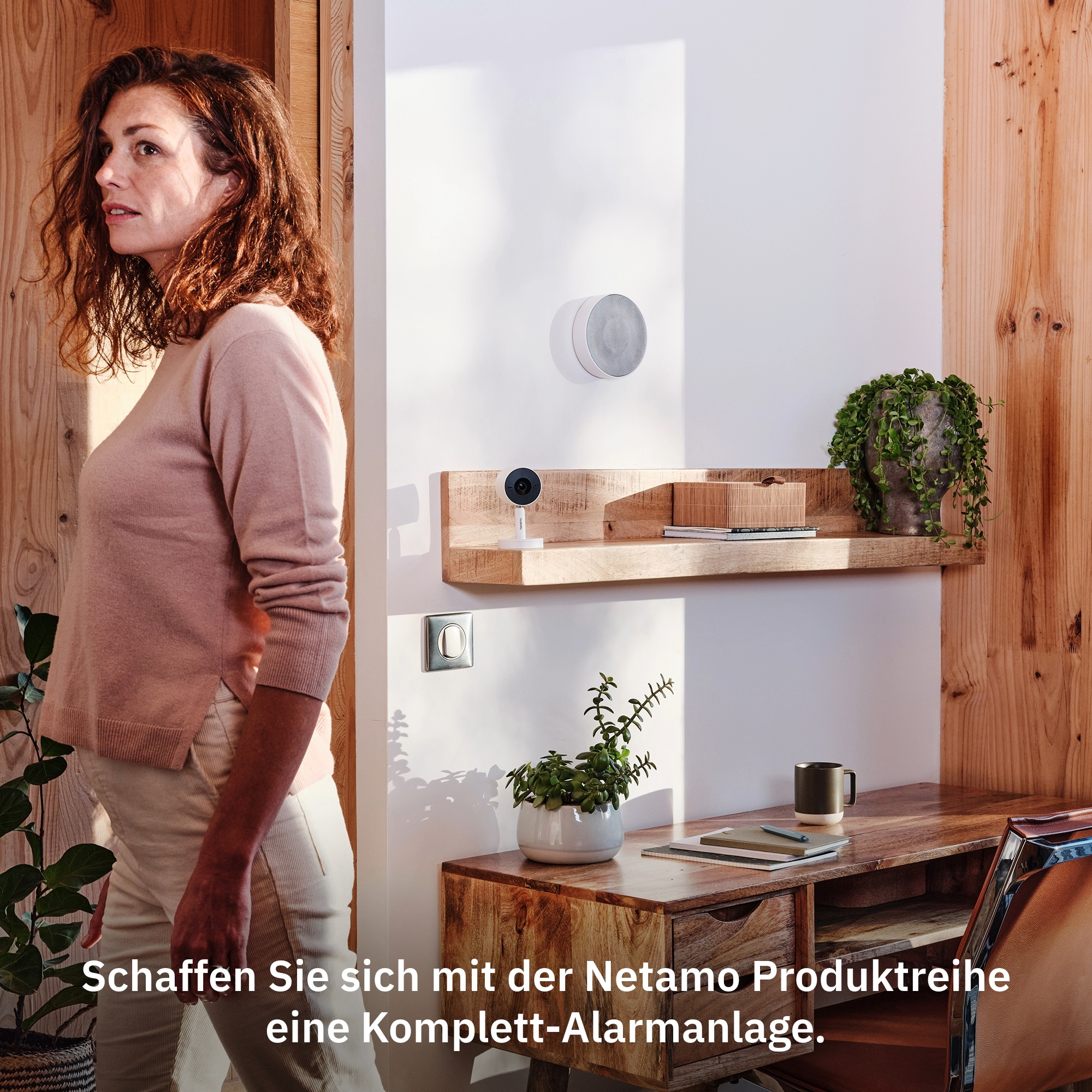 Frau schaut zur Kamera, neben einem Holztisch mit Smart-Home-Geräten.