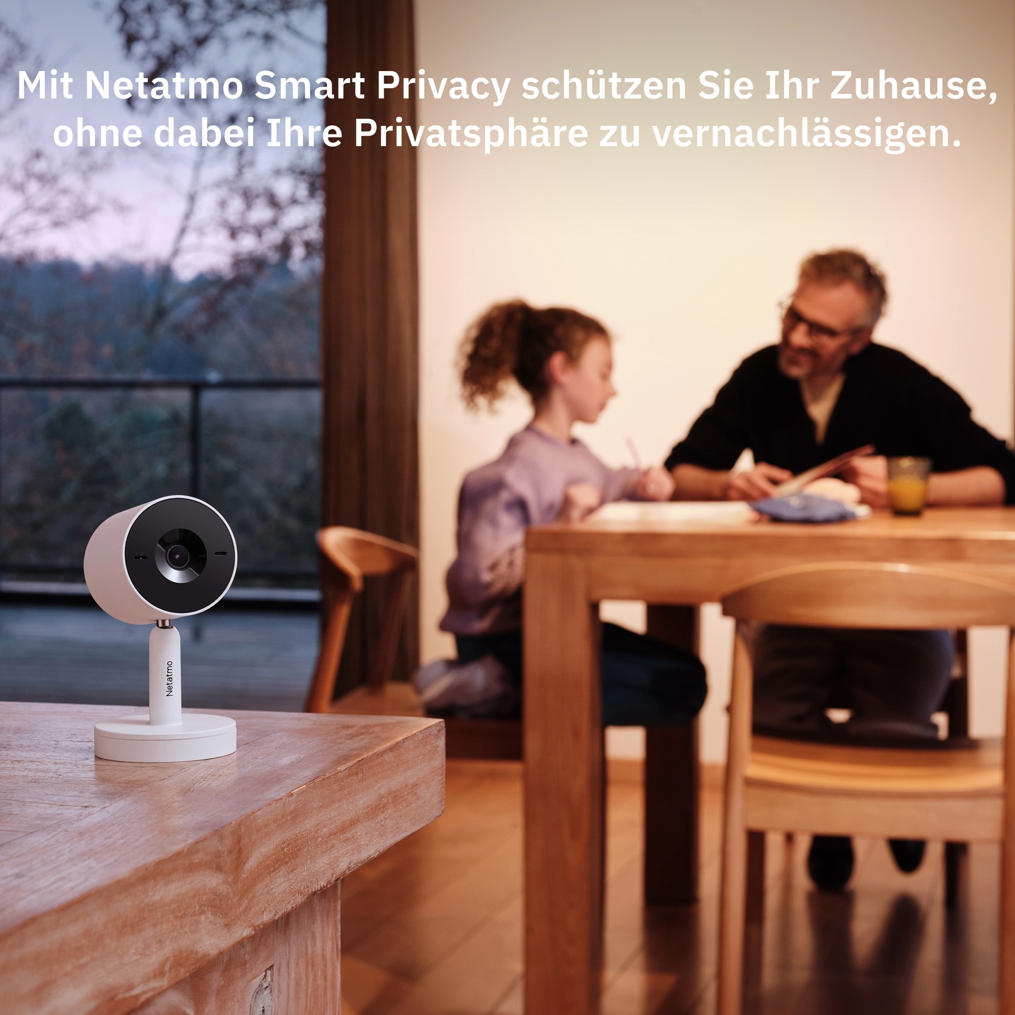 Eine Überwachungskamera auf einem Ständer auf einem Holztisch, mit Familie im Hintergrund.