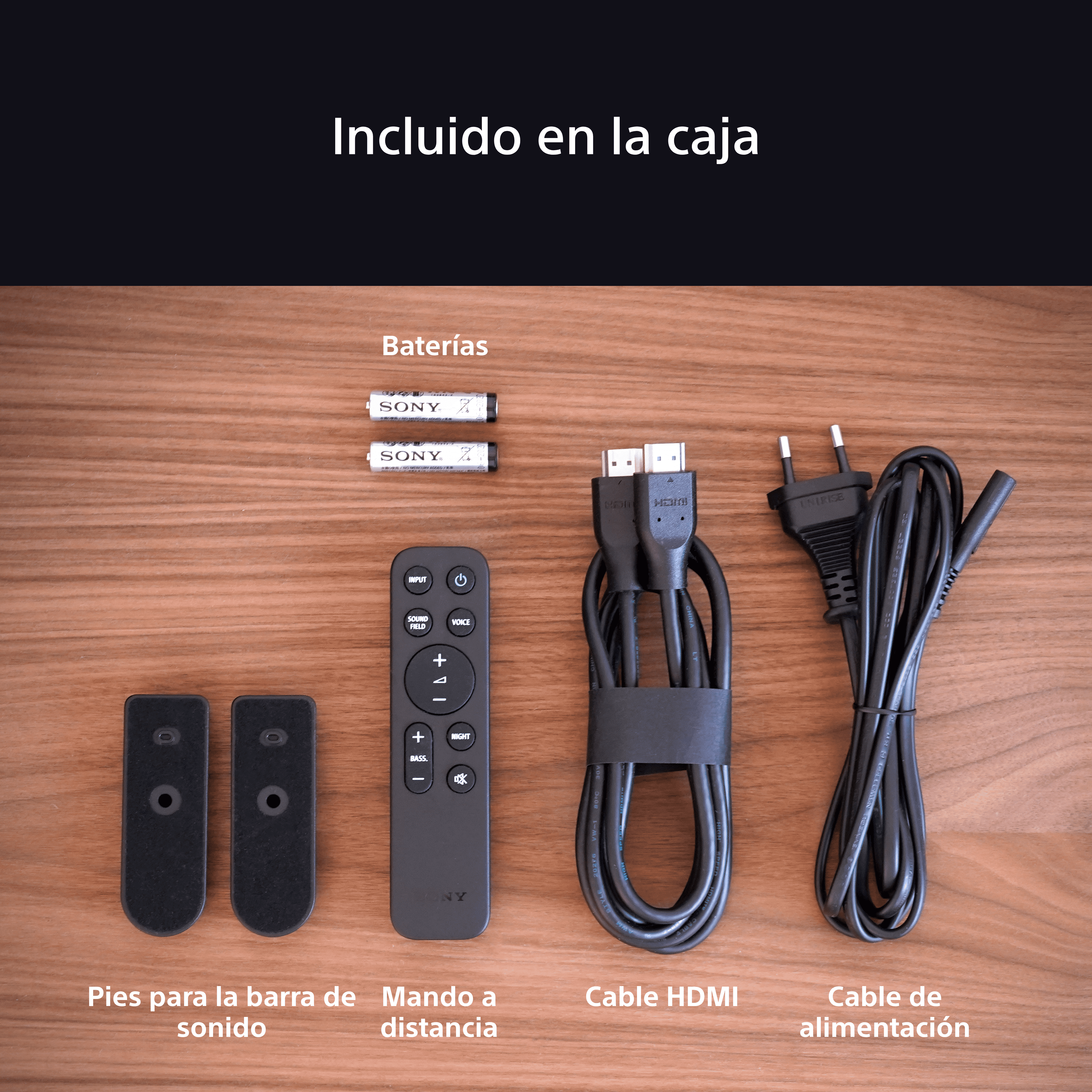 Contenido de la caja: dos mandos a distancia, pilas, un cable HDMI y un cable de alimentación. Todo sobre madera.