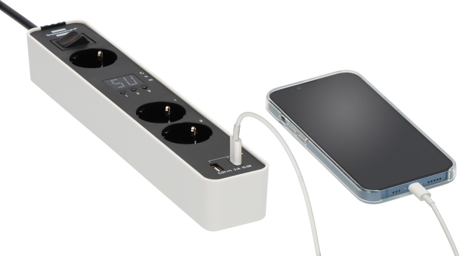 Eine weiße und schwarze Steckdosenleiste mit drei Steckdosen, einem ladenden Telefon.