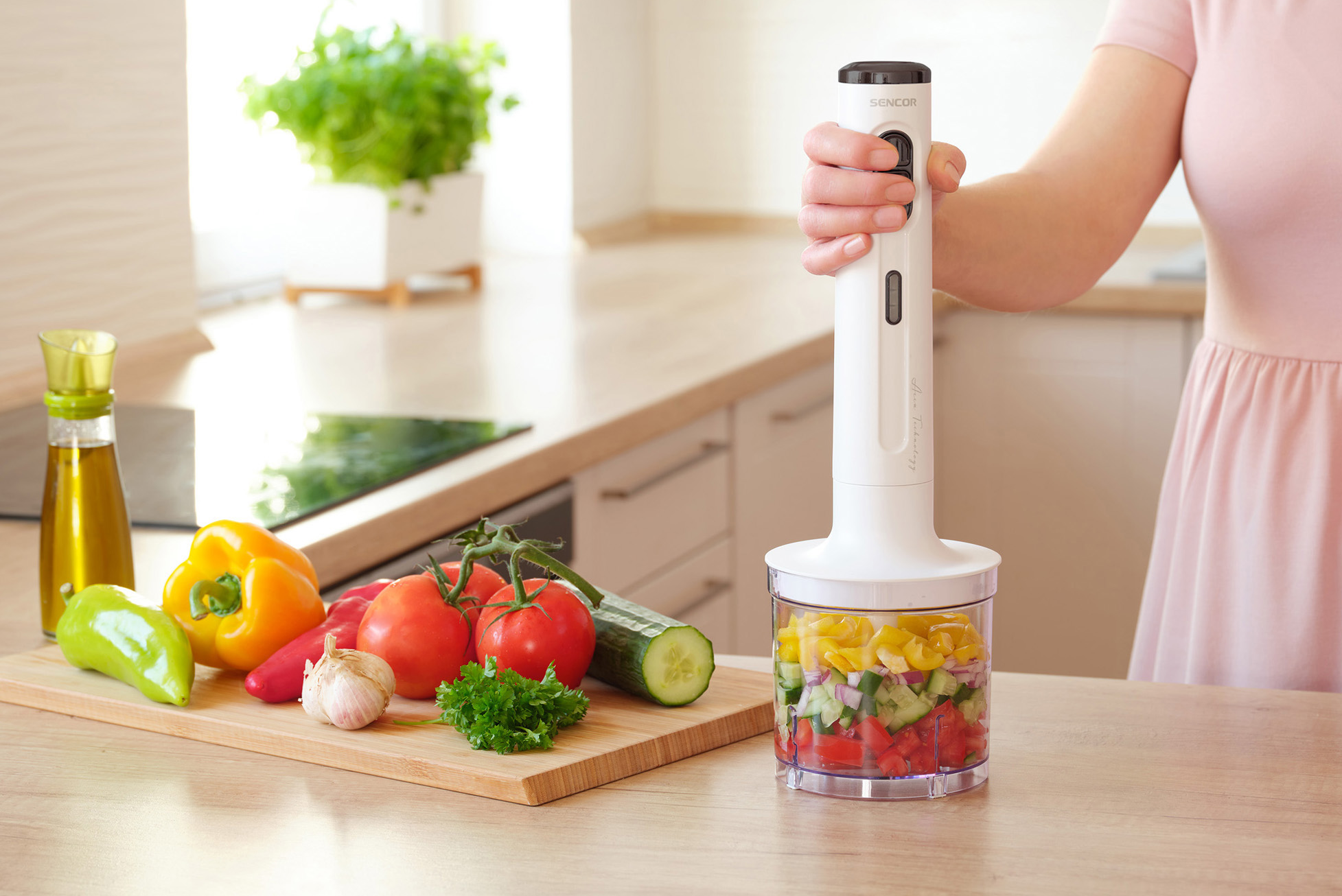 Nő kézi mixerrel friss aprított zöldségeket mixel.