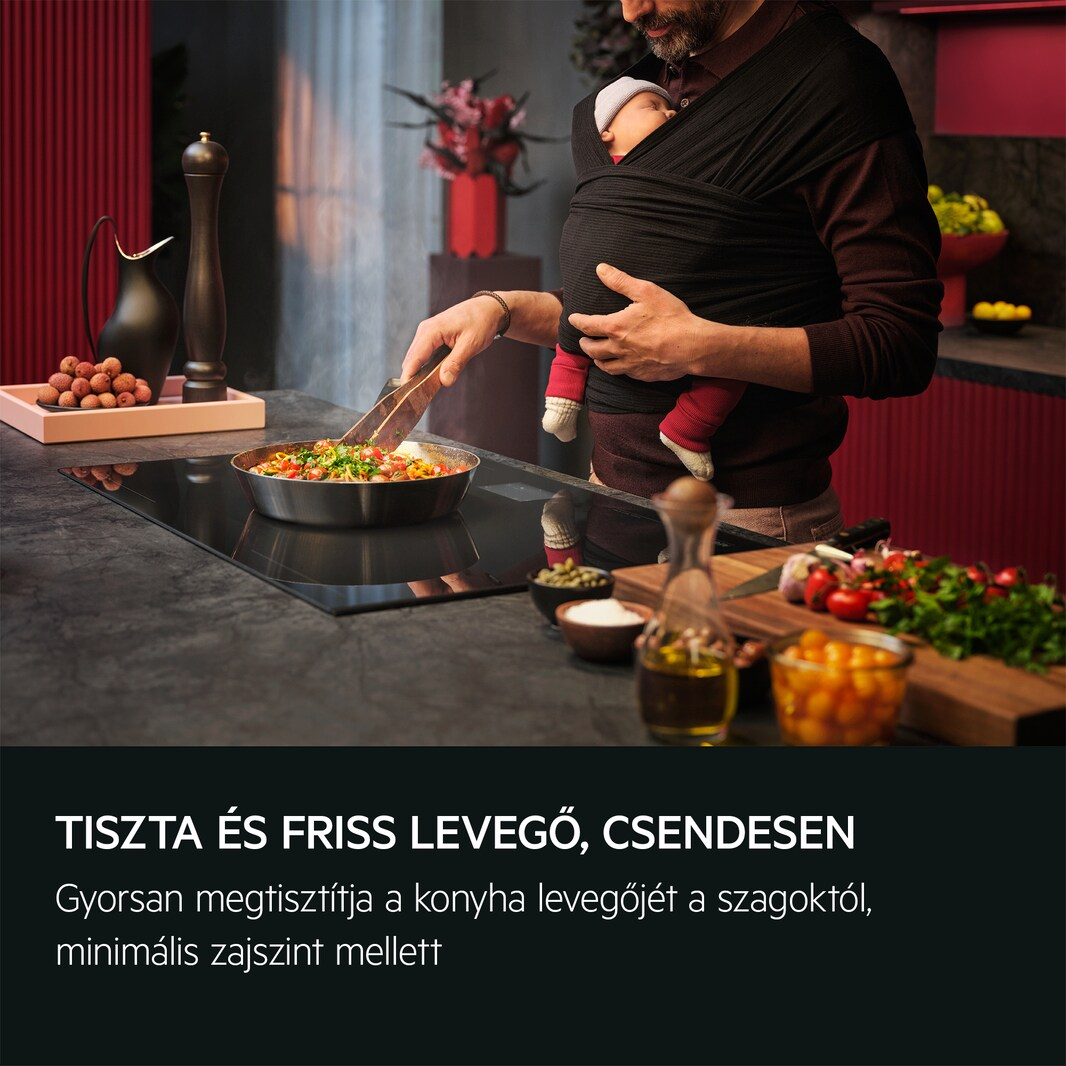 Személy főz, baba hordozóban. Serpenyő étellel a tűzhelyen. Magyar nyelvű szöveg.