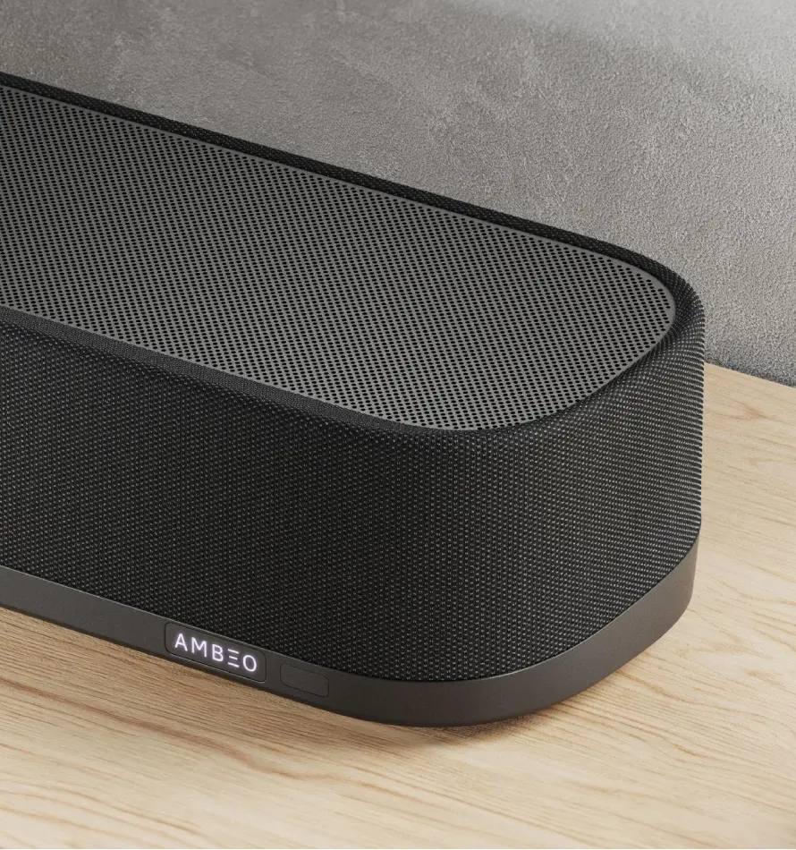 Eine schwarze Soundbar mit dem Wort AMBEO auf der Vorderseite, auf einem Holztisch.