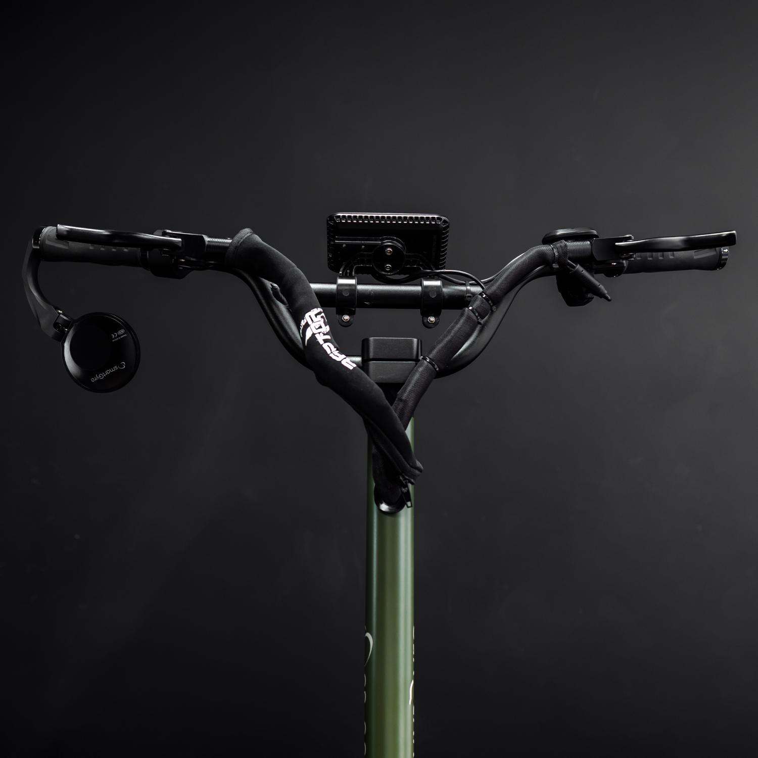 Un manillar de scooter, con empuñaduras negras, una luz y un espejo.