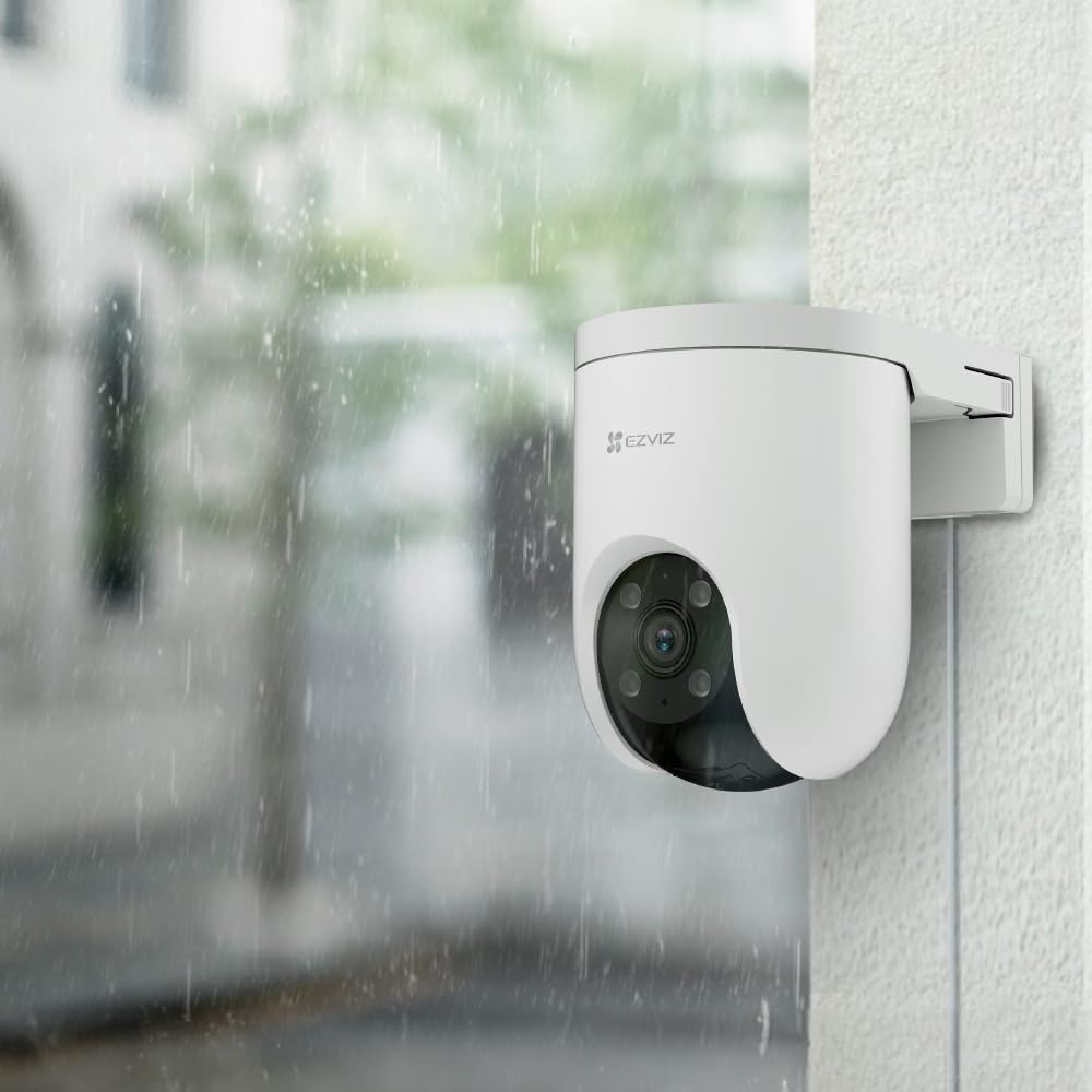 Cámara de seguridad exterior blanca en una pared. Lluvia cayendo en el fondo borroso.