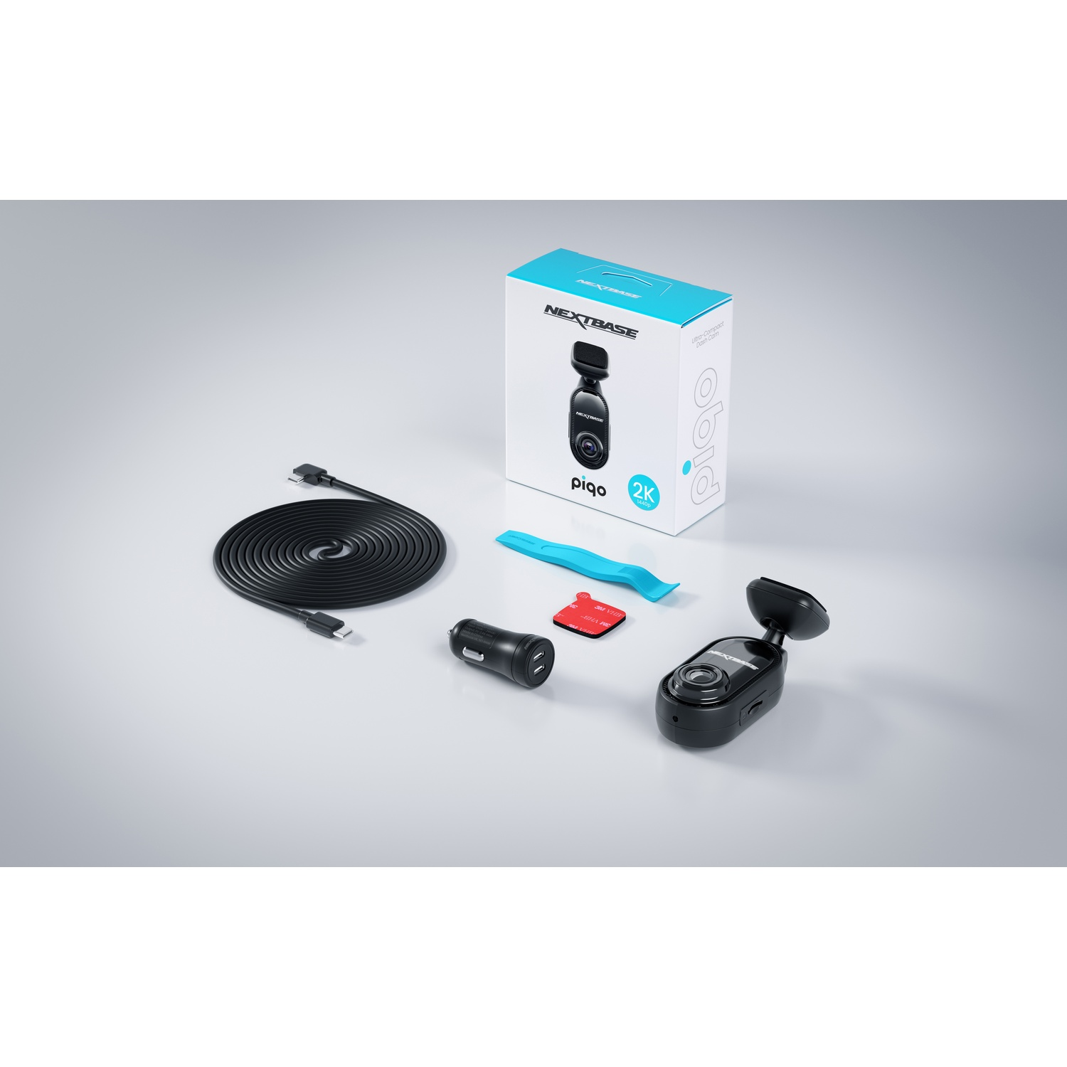 Kit de caméra de tableau de bord avec divers composants : caméra, câble USB, chargeur de voiture et accessoires de montage. Fond clair.