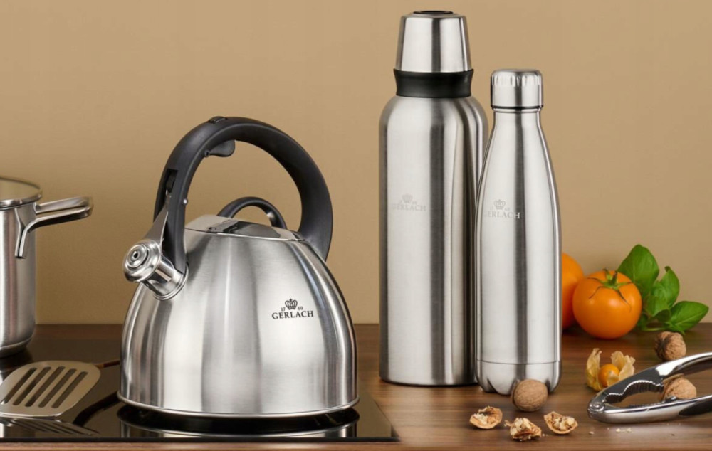 Czajnik ze stali nierdzewnej, dwie butelki na wodę i orzechy włoskie na drewnianym stole.