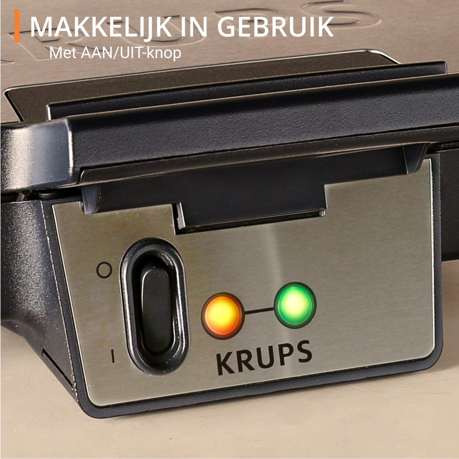 Close-up of a Krups waffle maker, with power button and indicator lights. The green light is on.