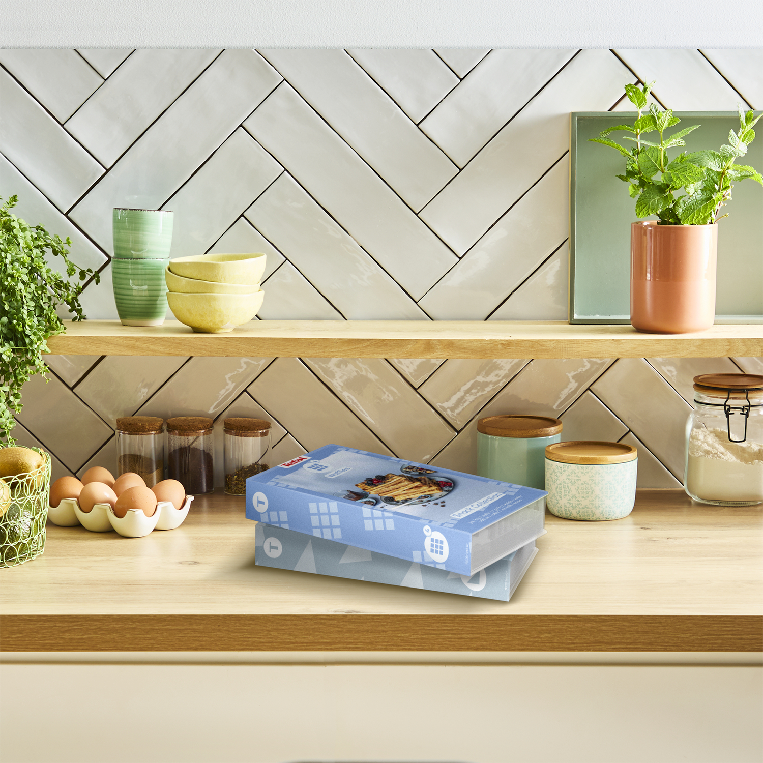 Kitchen scene with shelves, plants, and various containers. Two boxes are on the wooden counter.