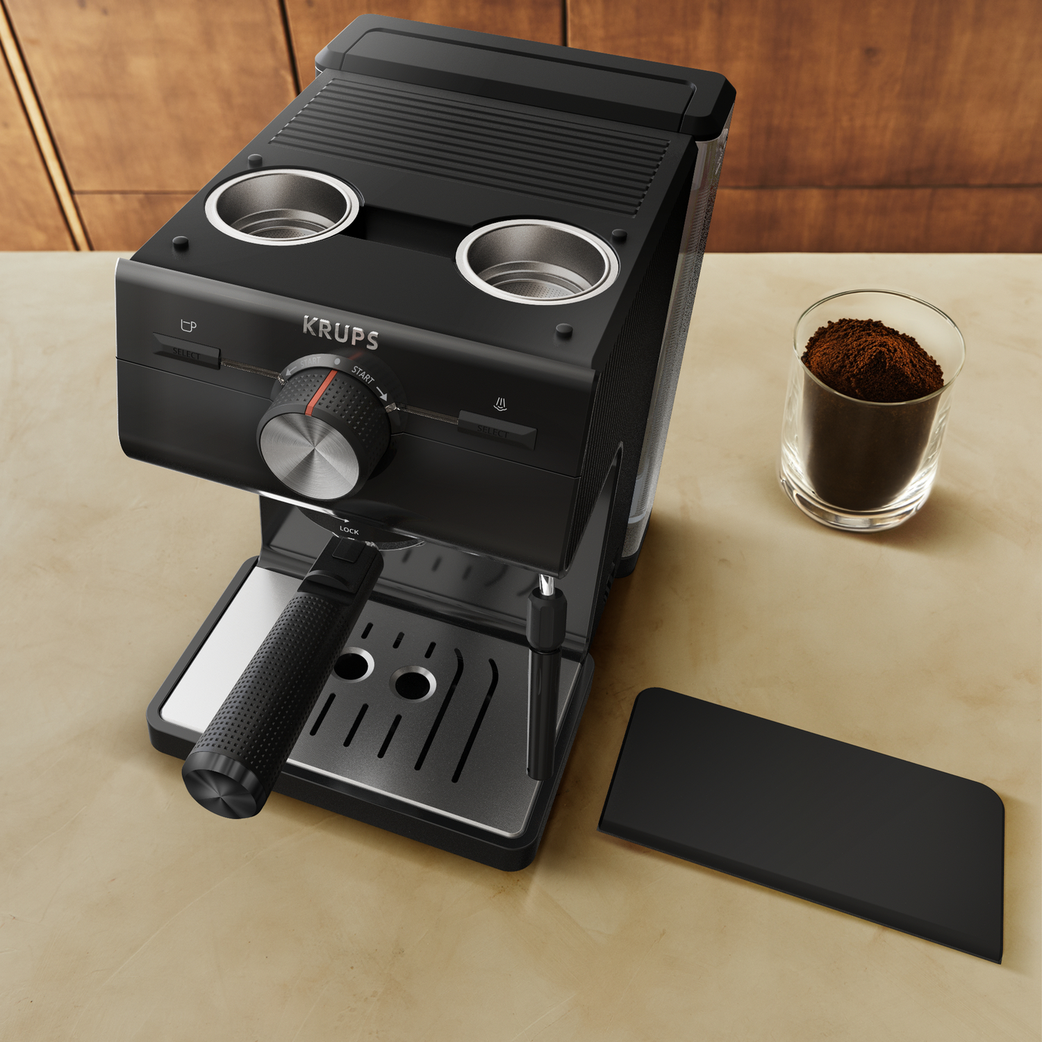 Zwarte Krups espressomachine met koffiedik in een glas en een zwart bord.