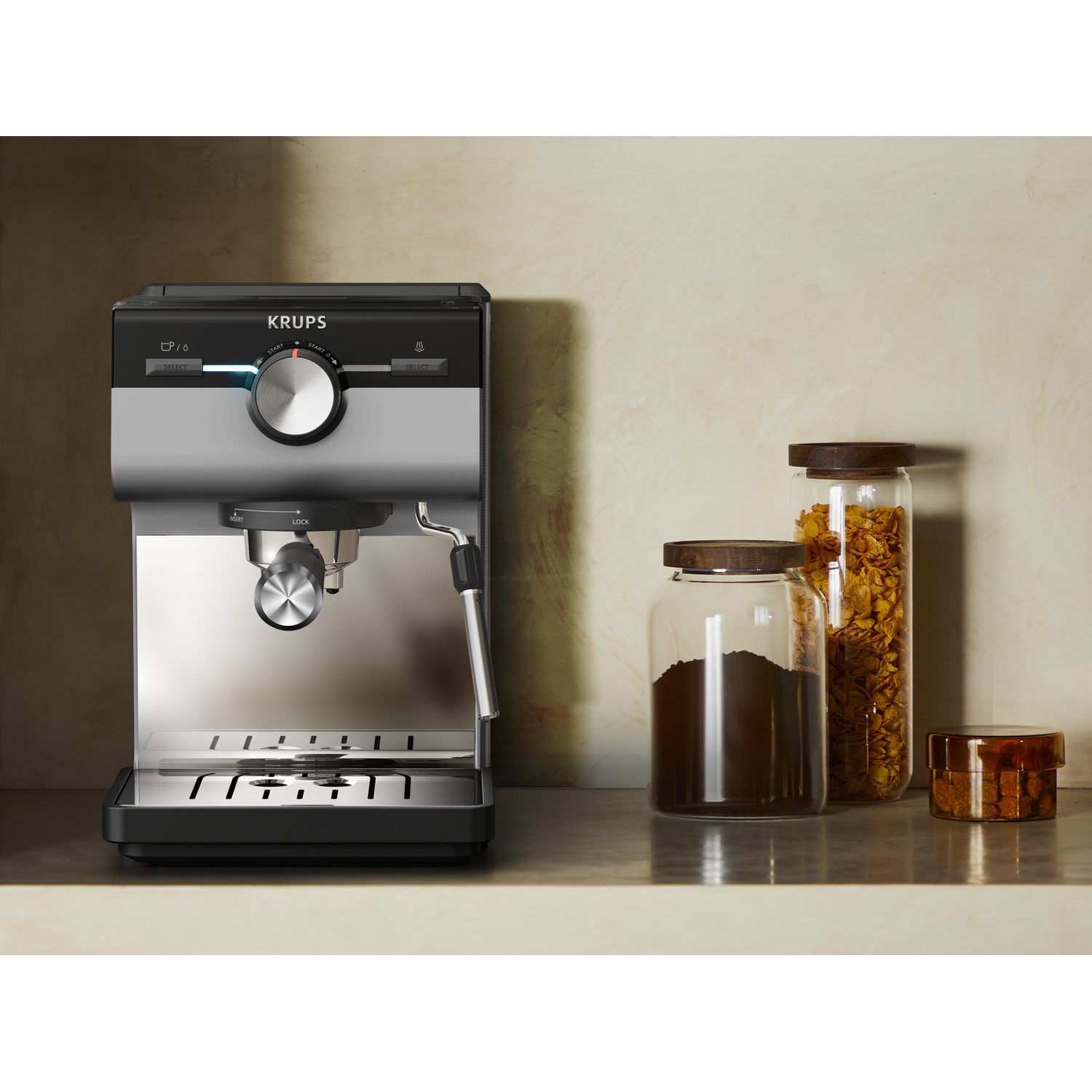 Een zilveren en zwarte Krups espressomachine staat op een aanrecht met potten koffie.
