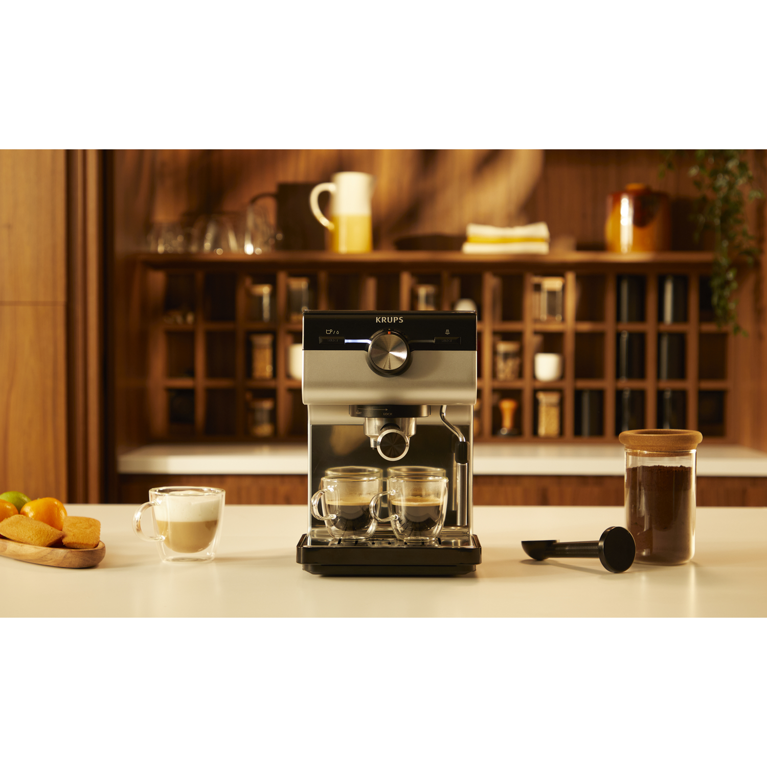 Espressomachine met twee glazen kopjes koffie. Koffiedik en een lepel rechts.