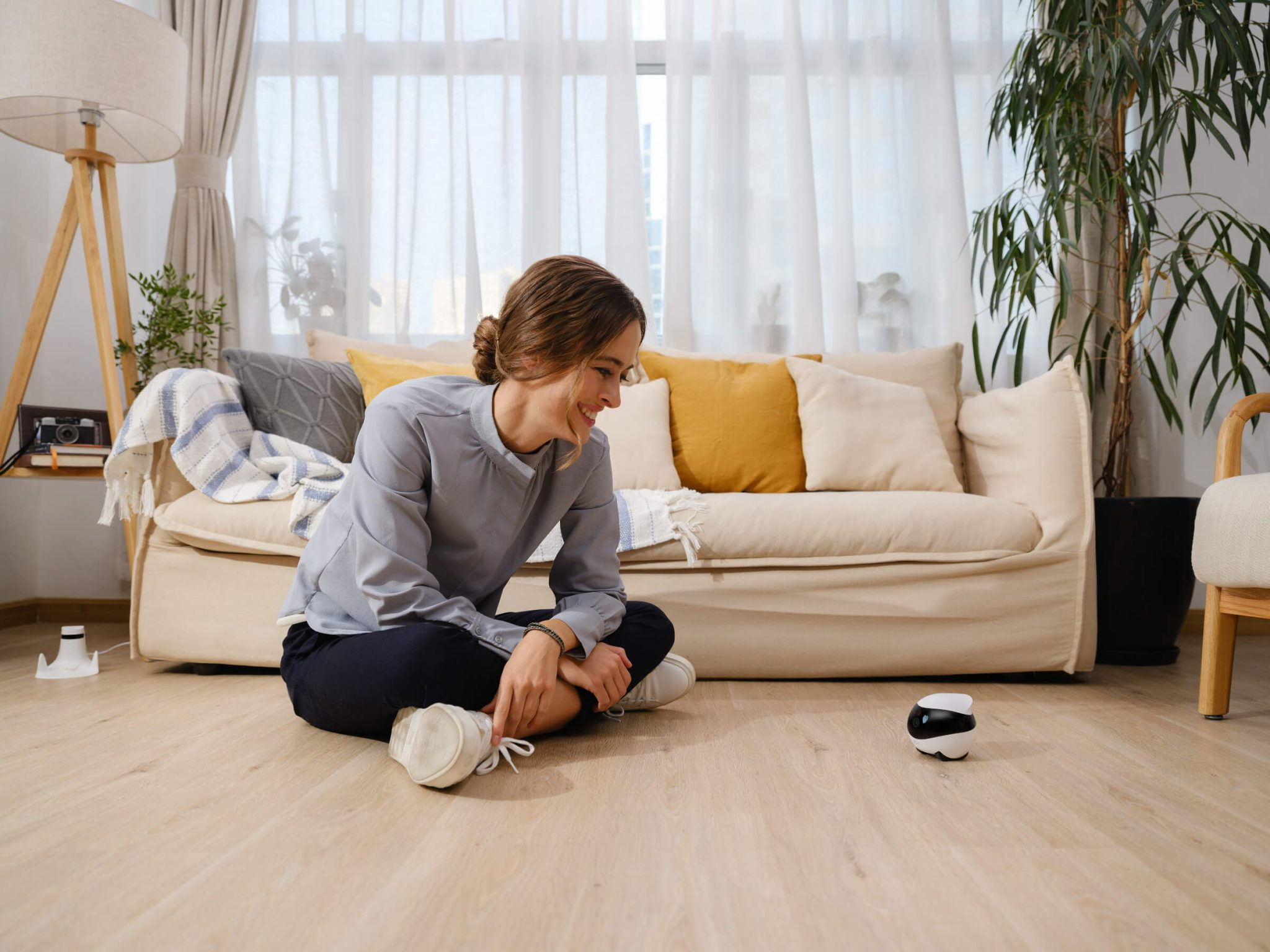 Kobieta siedzi, patrząc na małego czarnego robota.