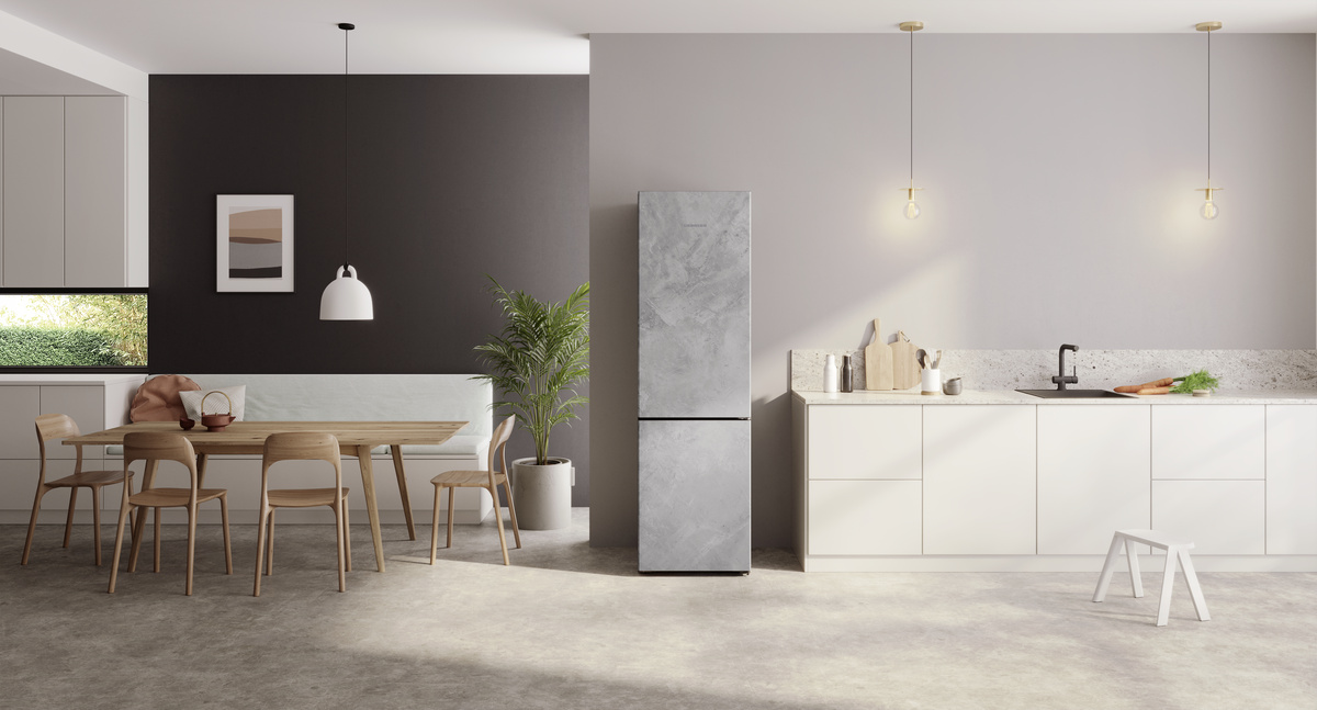 Eine moderne Küche mit einem grauen Kühlschrank, einem Tisch mit Stühlen und einer weißen Arbeitsplatte.