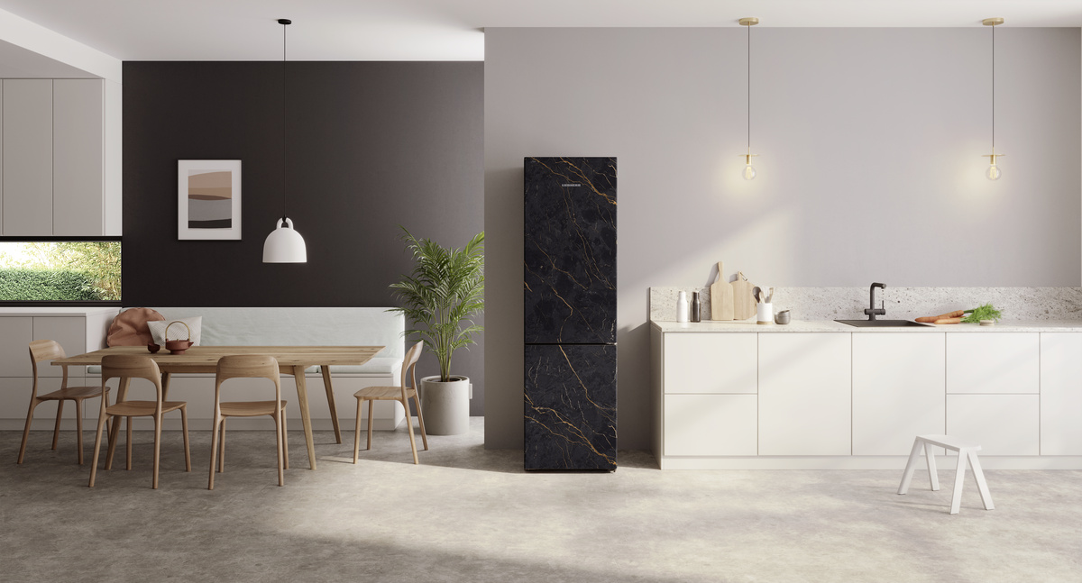 Küche mit schwarzem Marmor-Kühlschrank, Holztisch, weißen Schränken und grauer Wand.