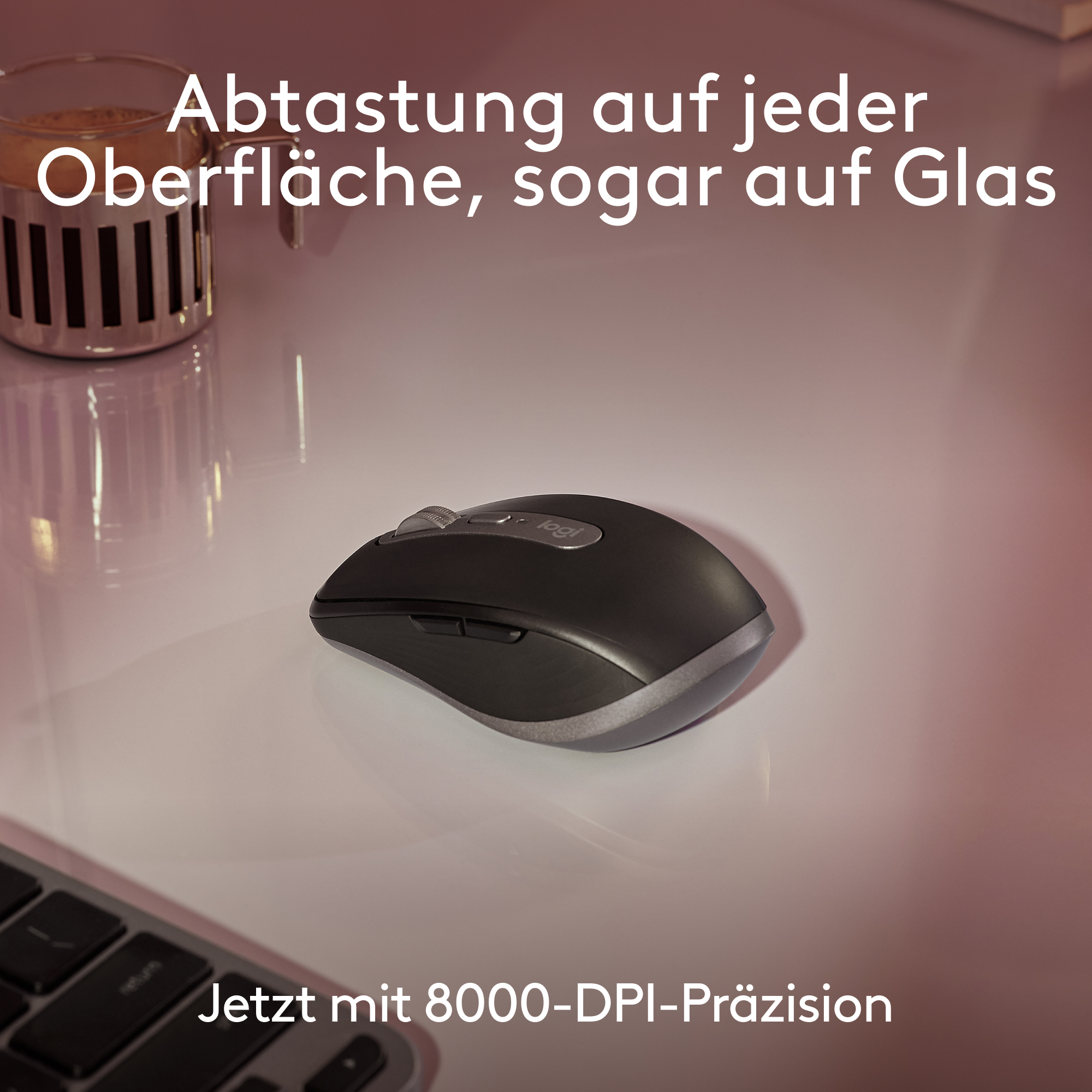 Eine schwarze Computermaus auf einer weißen Oberfläche mit einem Glas Flüssigkeit und einer Tastatur im Hintergrund.