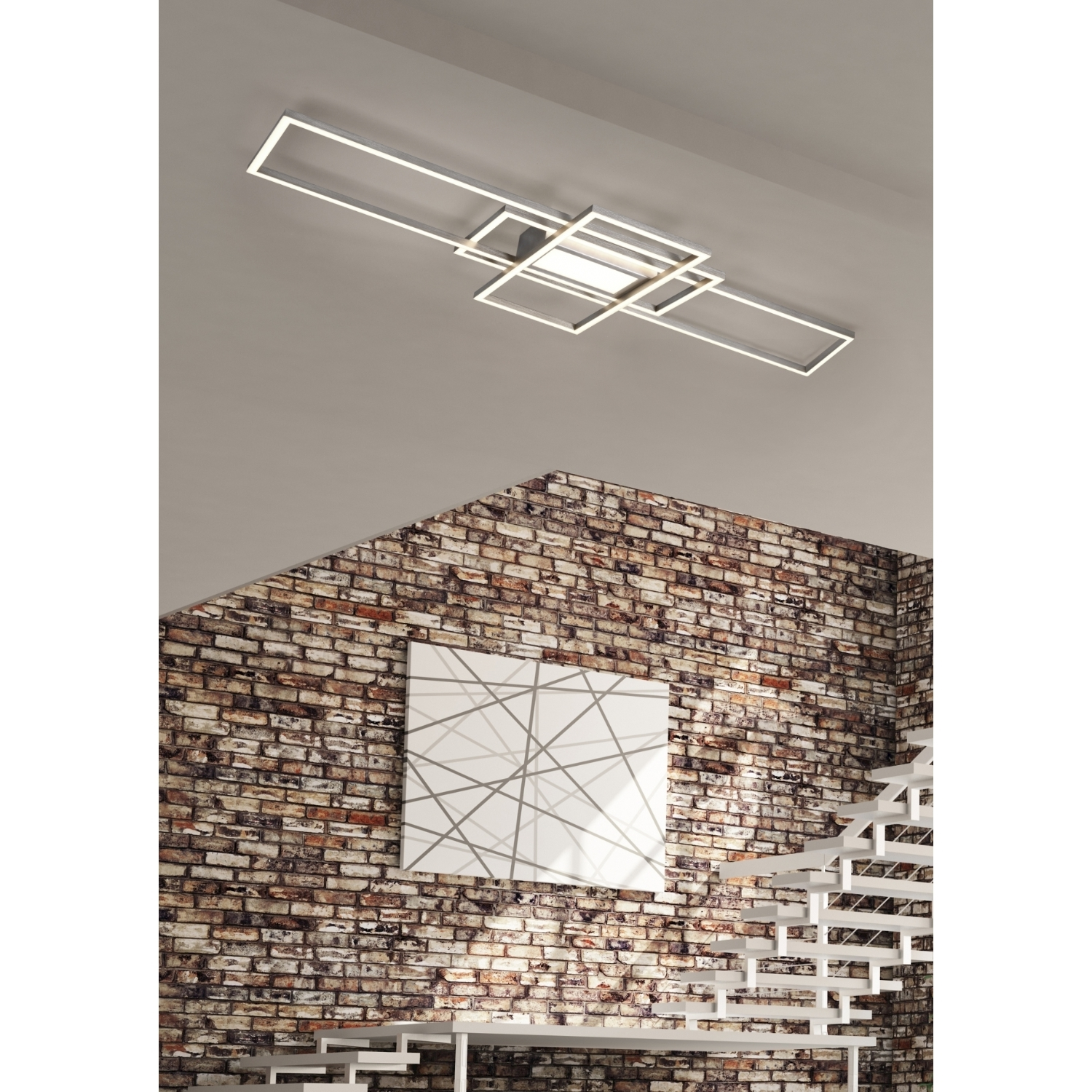Lampada da soffitto moderna con luci rettangolari, su un muro di mattoni con scale bianche e opere d'arte.