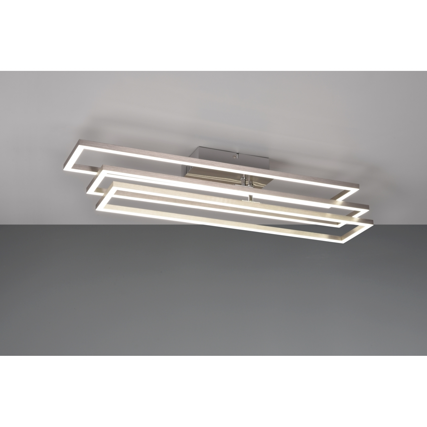Un moderno apparecchio di illuminazione a soffitto con pannelli luminosi rettangolari, angolati e sovrapposti.