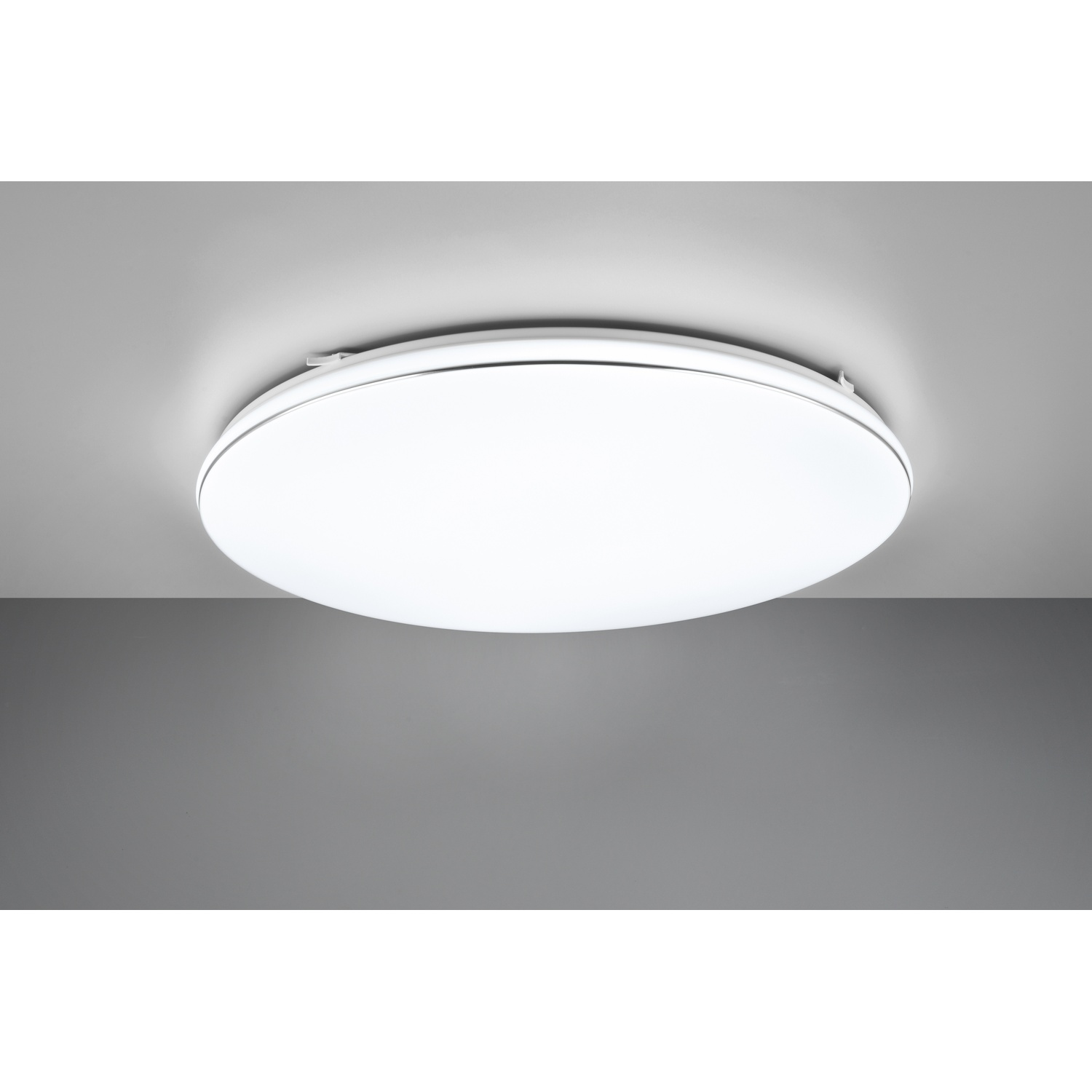 Un apparecchio di illuminazione rotondo e bianco è montato su un soffitto grigio, creando un'illuminazione luminosa.