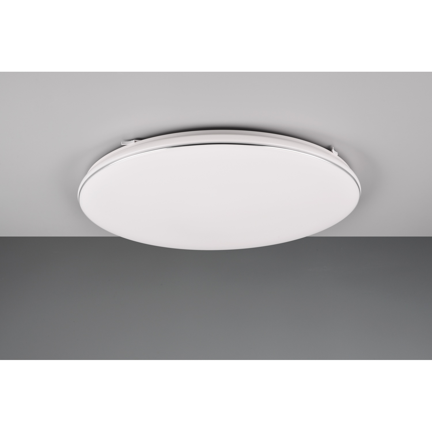 Un apparecchio di illuminazione a soffitto bianco, rotondo, contro un soffitto grigio.